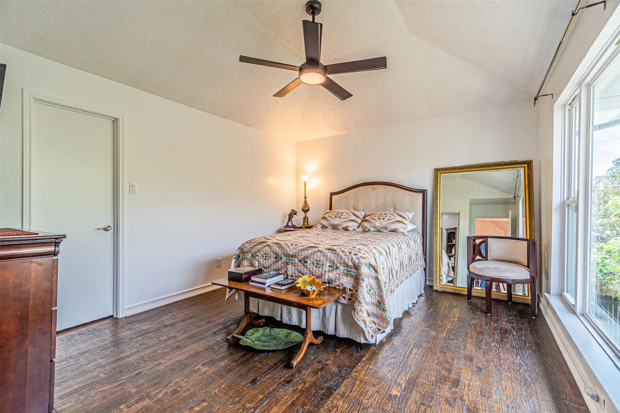 Room featuring wood-finish flooring, a ceiling fan with integrated lighting, and white walls