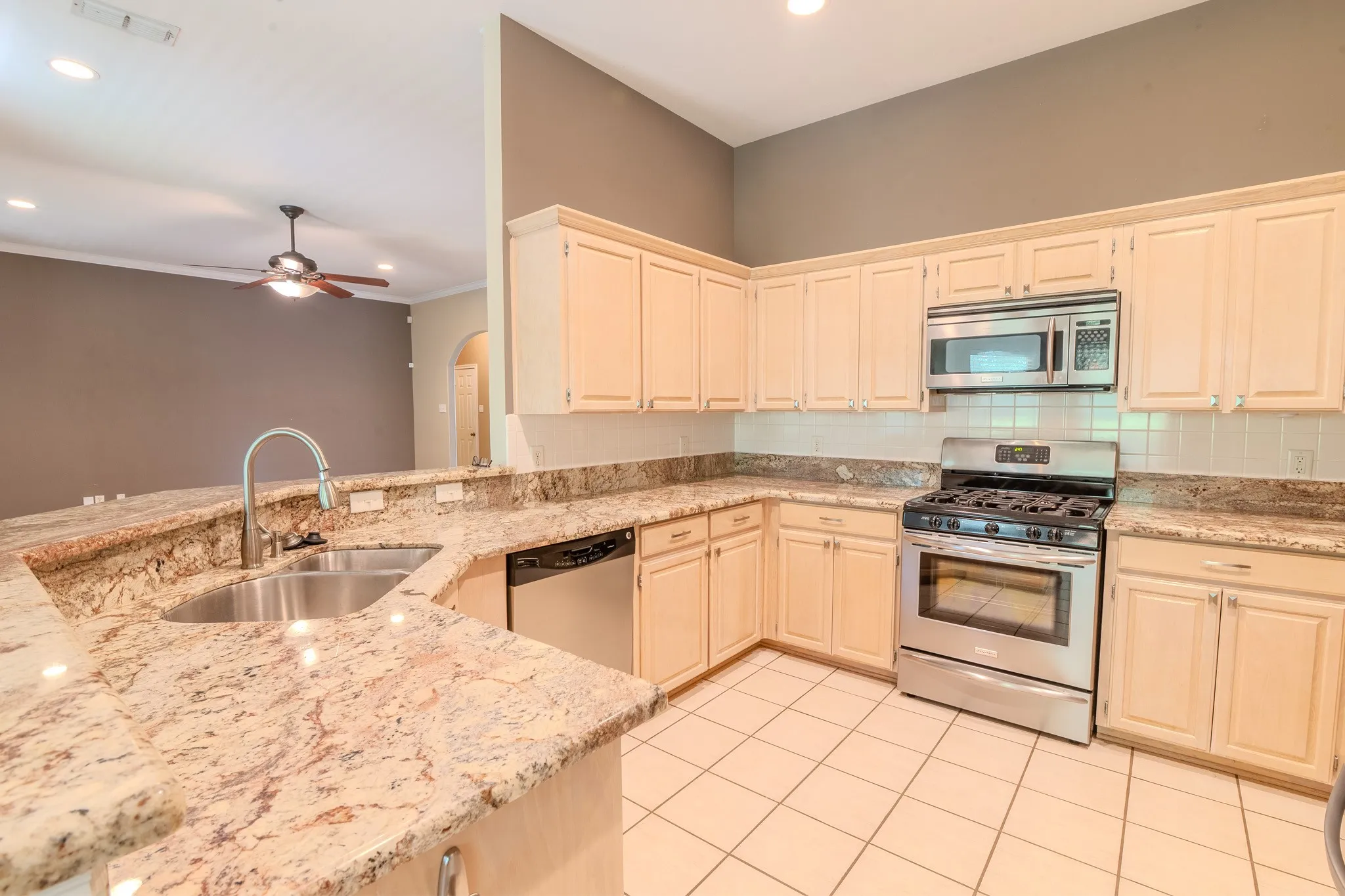 Kitchen featuring light-toned cabinetry, stainless steel appliances, and a tile backsplash
