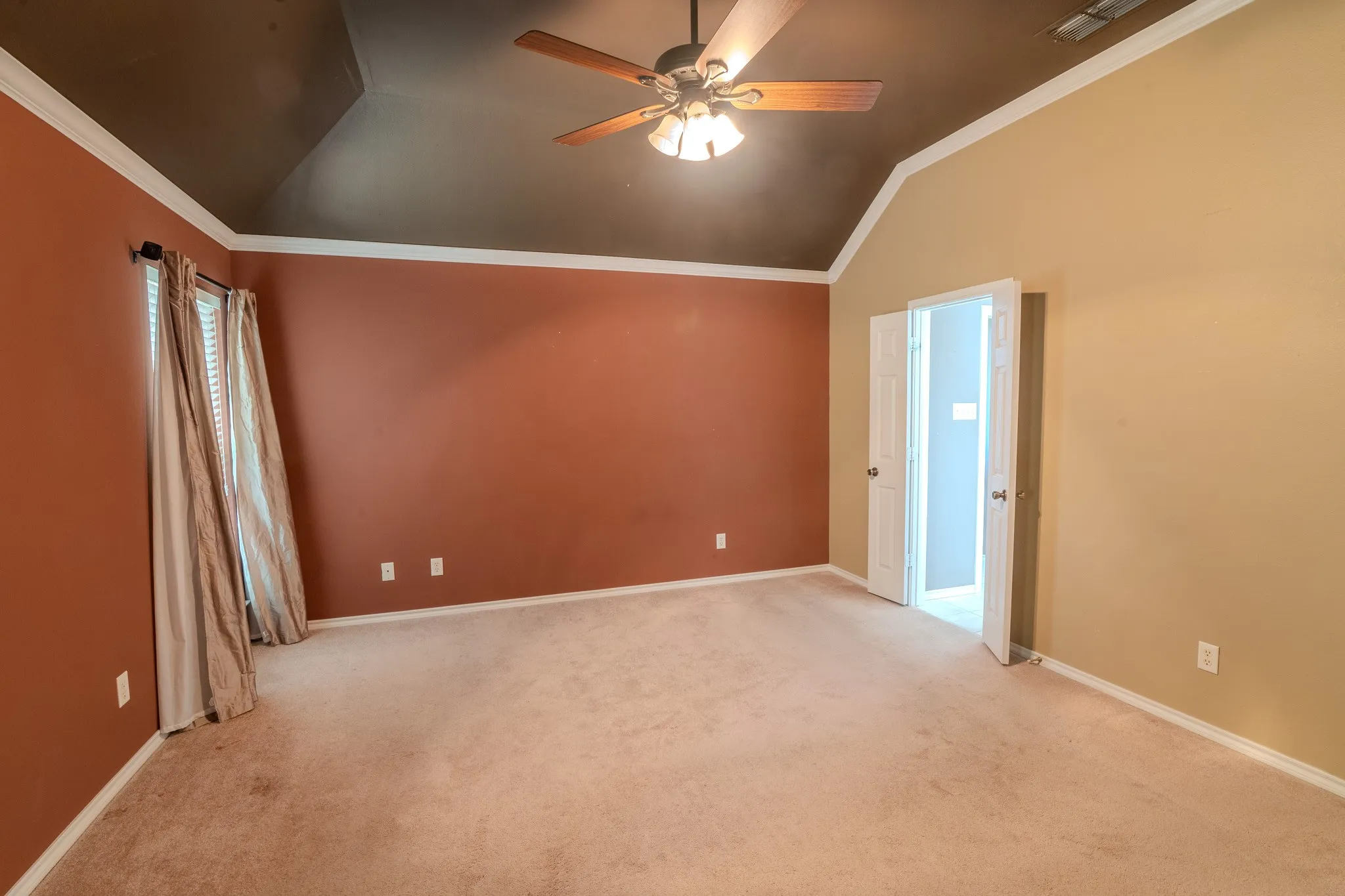 Spacious room with a vaulted ceiling, ceiling fan with integrated lighting, and carpet flooring
