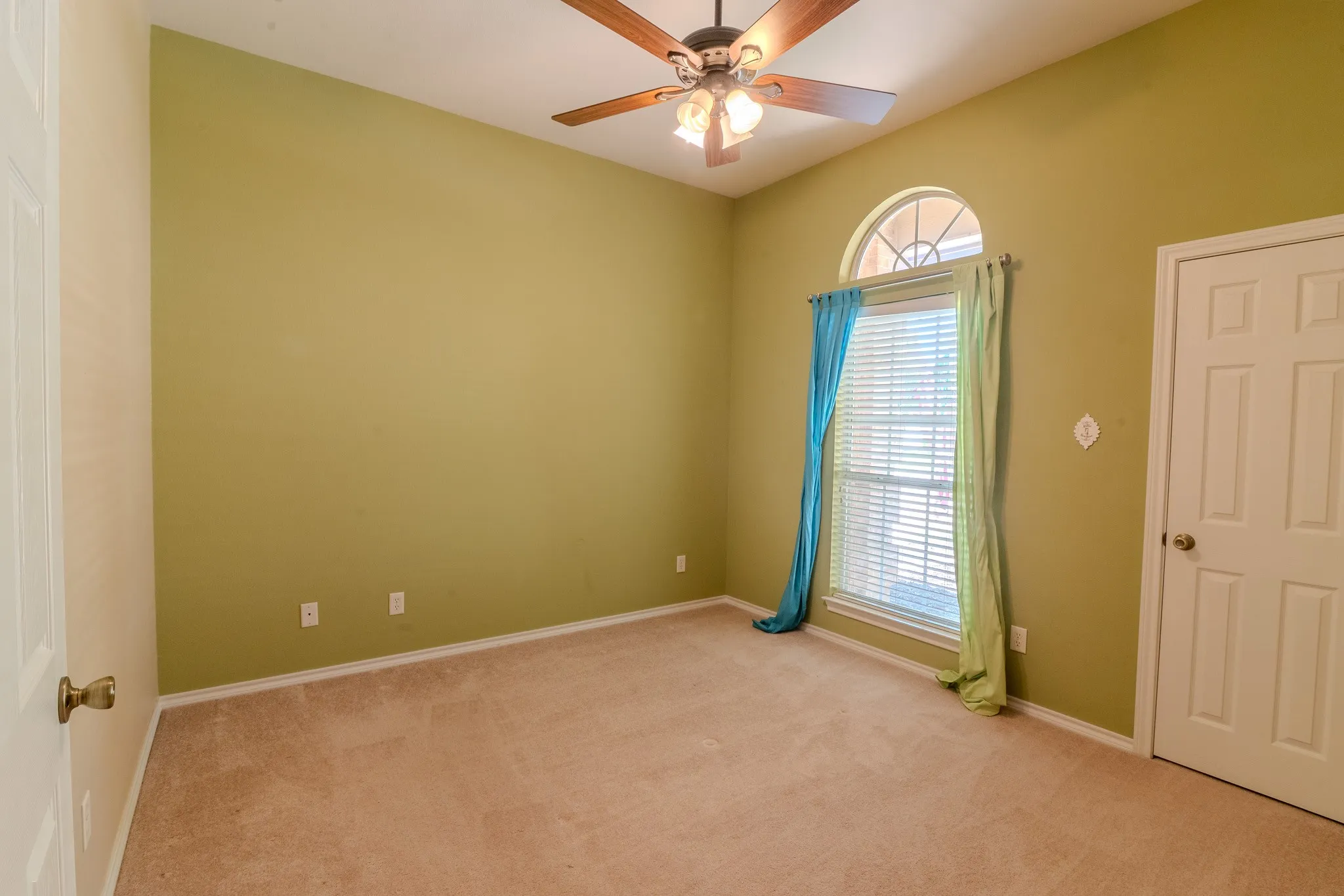 Room featuring a vaulted ceiling and a wood-finish ceiling fan with integrated lighting