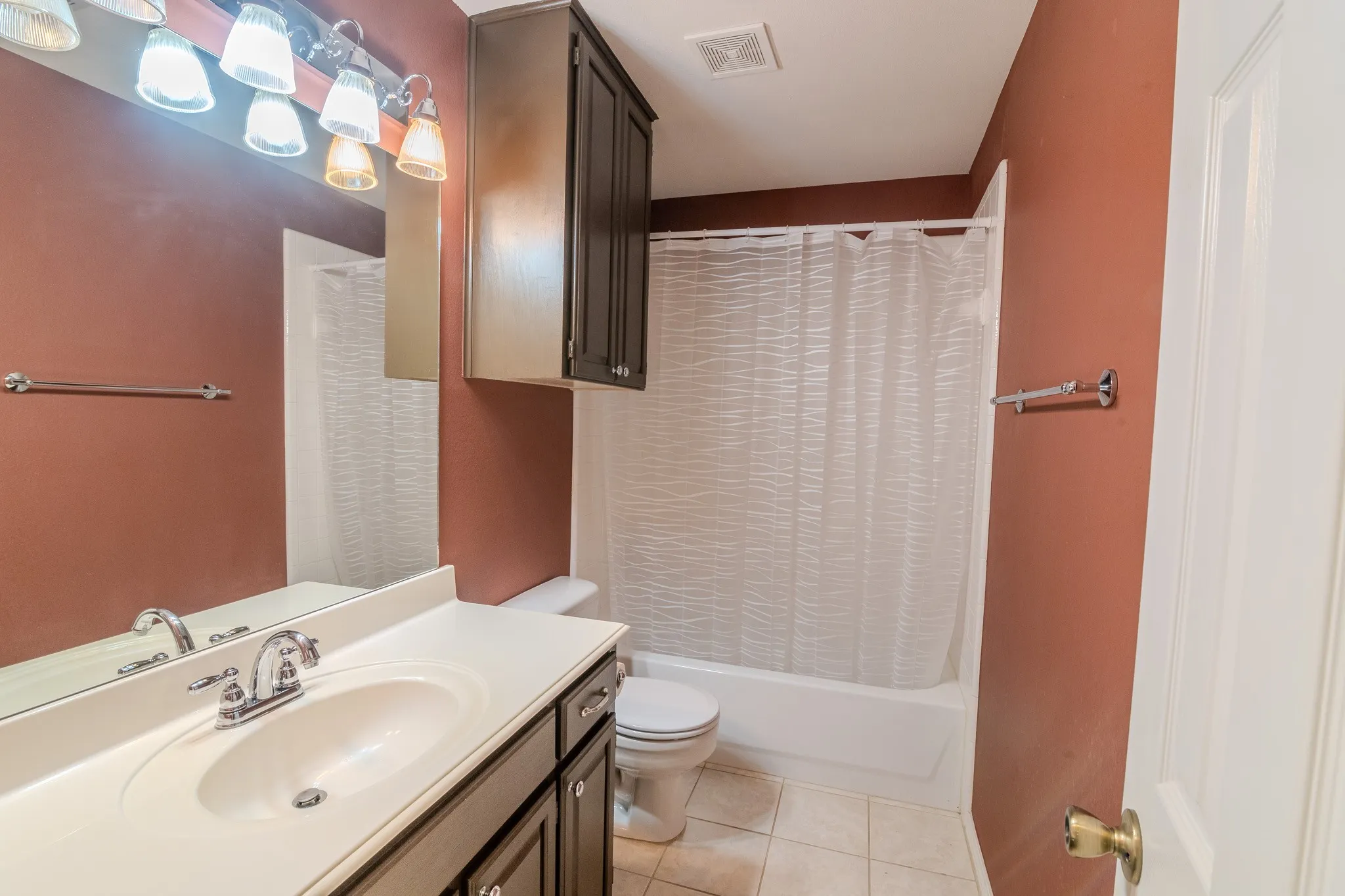 Bathroom featuring a vanity with an integrated sink, chrome faucet, and dark wood-finish cabinetry