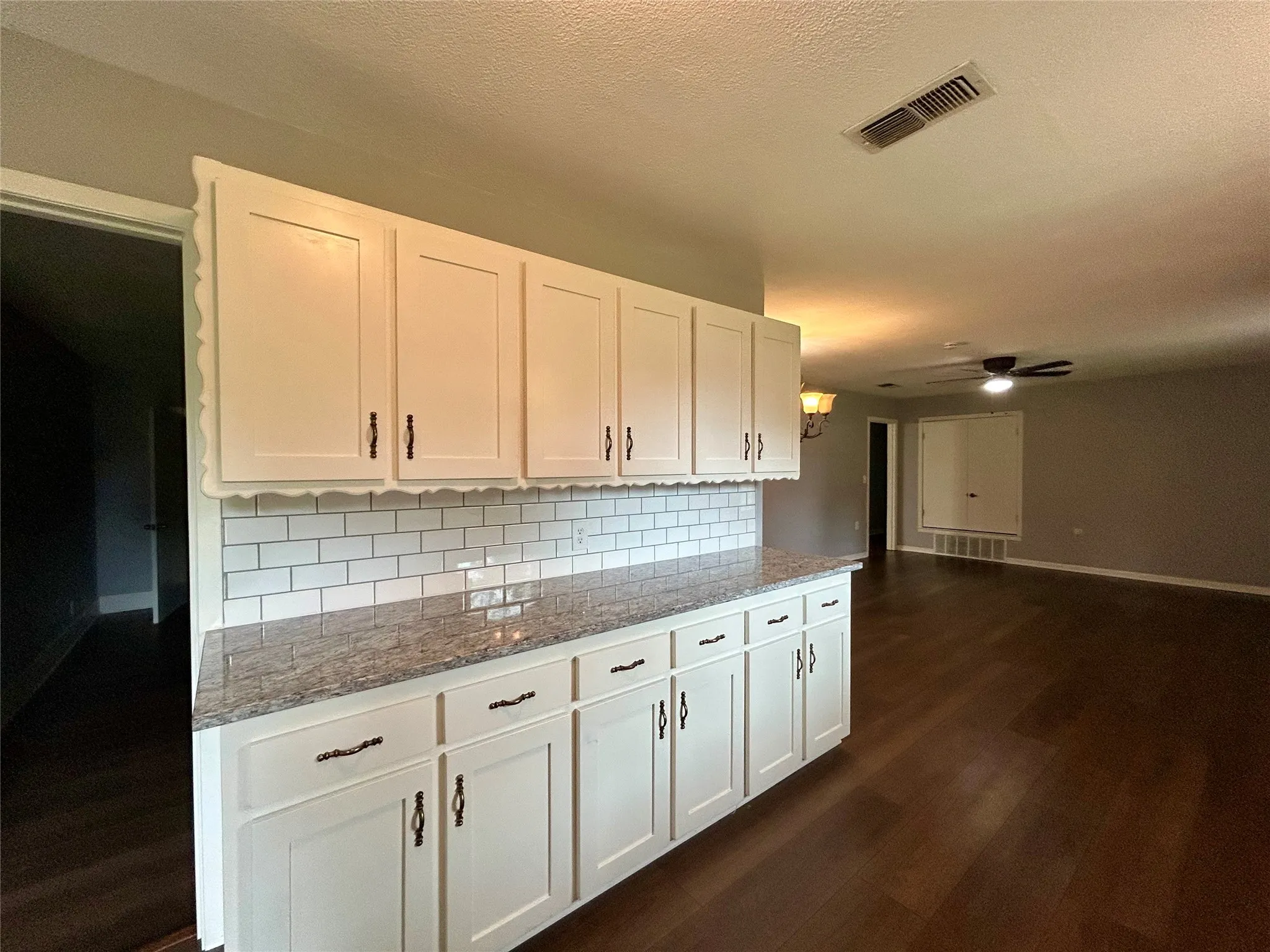 White cabinetry with black hardware, subway tile backsplash, and a speckled countertop