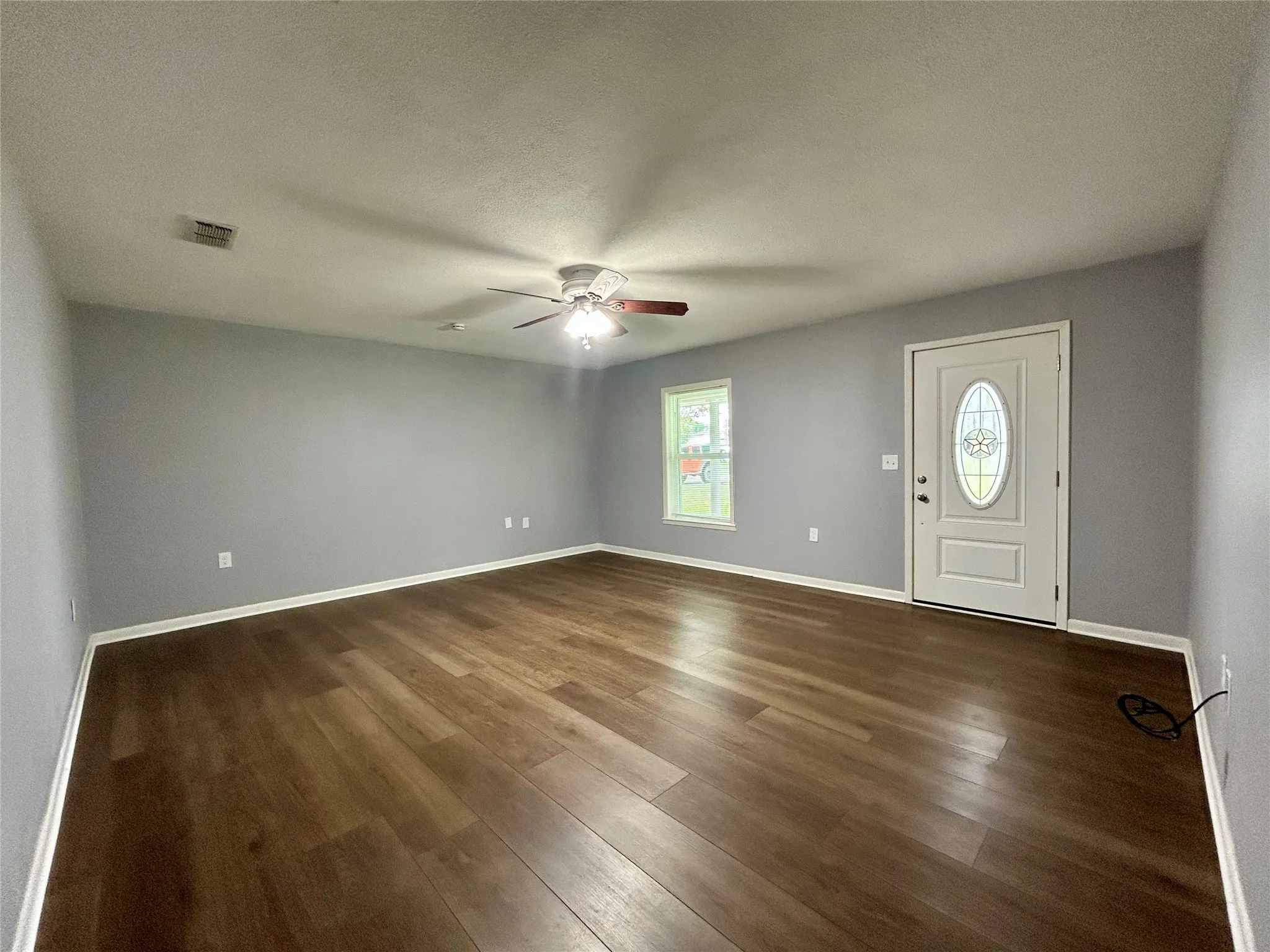 Spacious living area featuring wood-finish flooring, light gray wall tones, and white trim