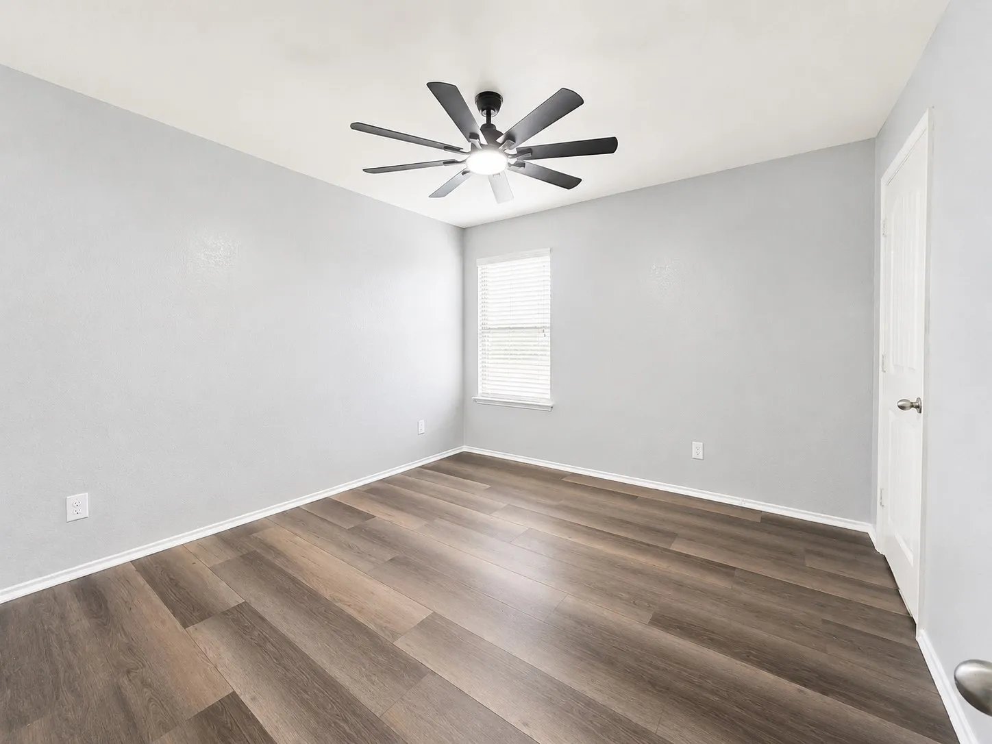 Room featuring wood-finish flooring, a modern ceiling fan, and a window with blinds