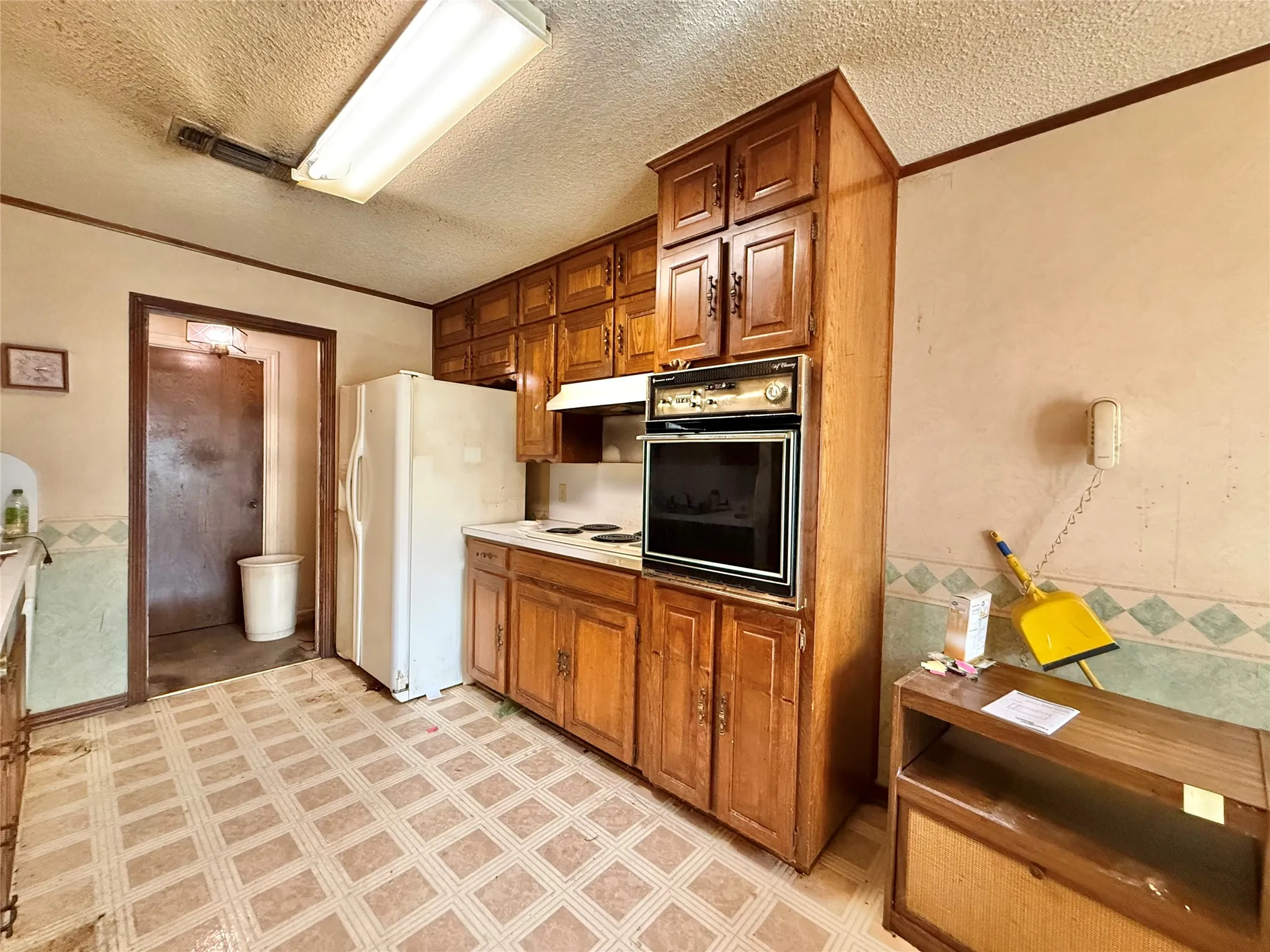 Kitchen featuring wood cabinetry, white appliances, and patterned flooring