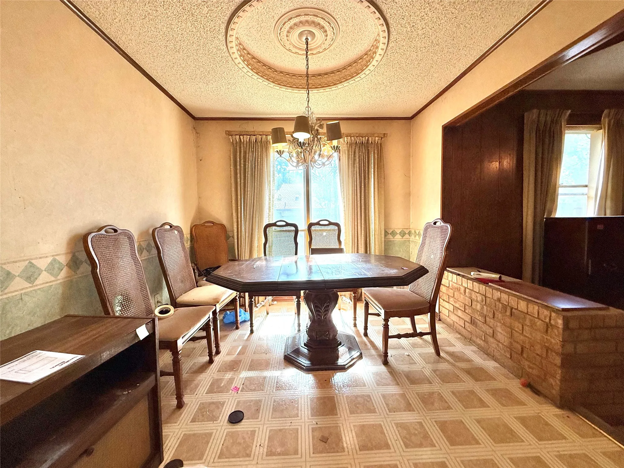 Dining area featuring a decorative medallion ceiling, overhead chandelier, and patterned floor tile