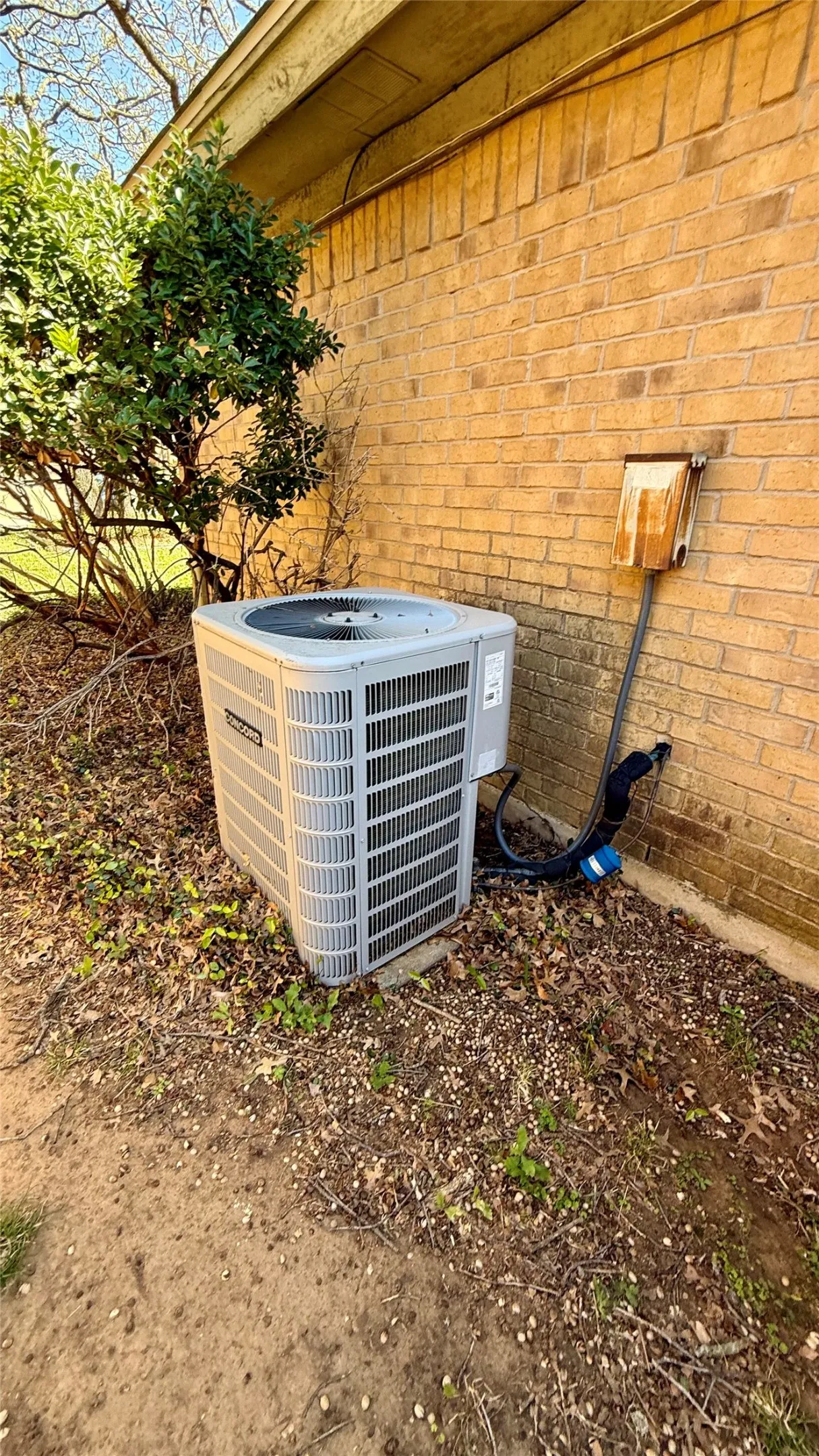 Exterior brick wall with a large HVAC unit on a concrete pad