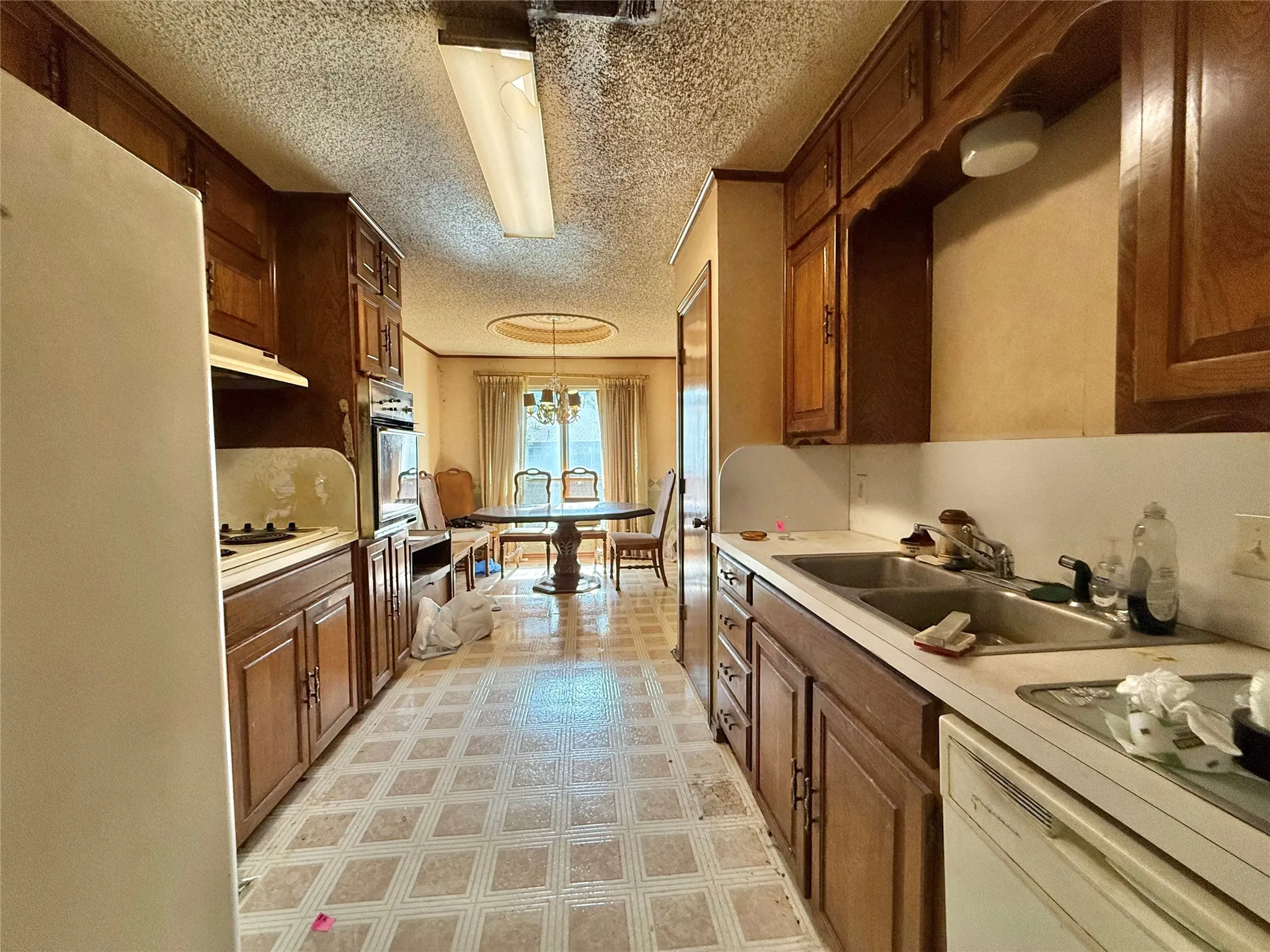 Galley kitchen featuring wood cabinetry, laminate countertops, and patterned vinyl flooring