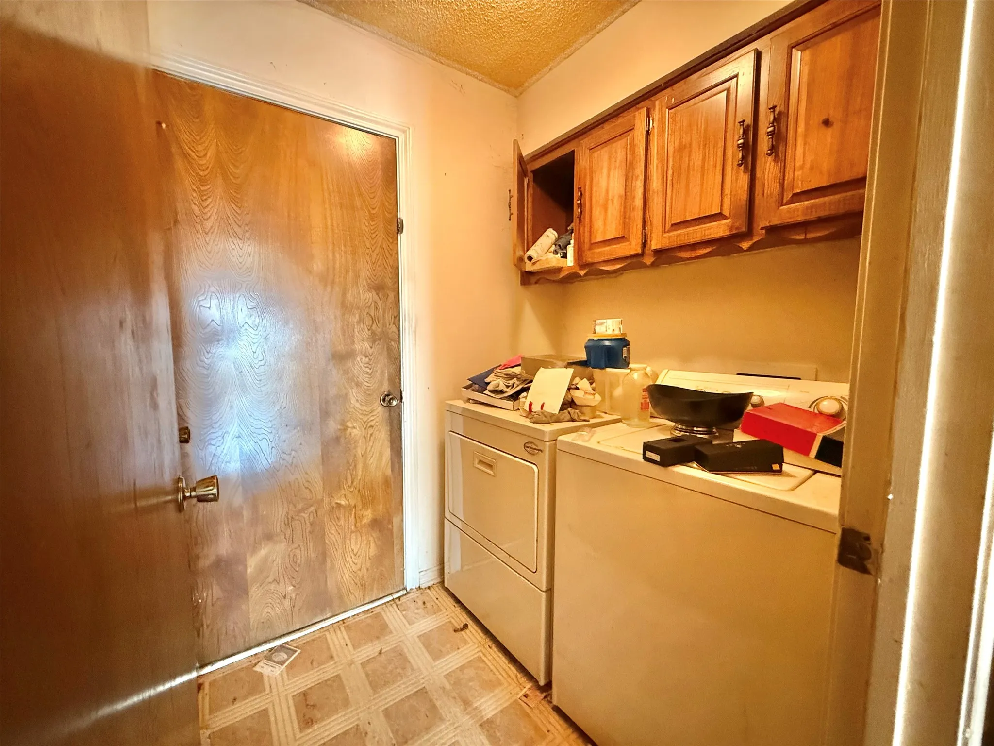 Laundry area with overhead wood cabinetry and tile-patterned flooring
