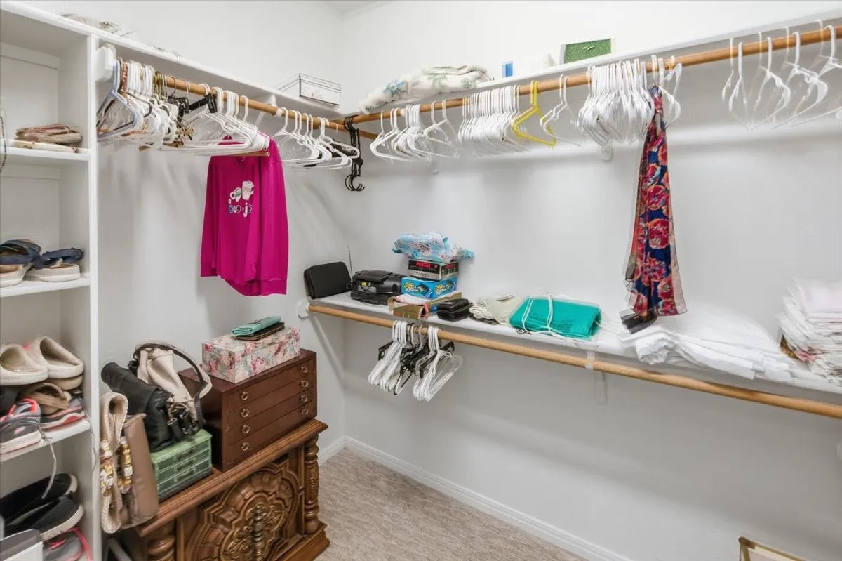 Spacious walk-in closet featuring built-in shelving, two levels of hanging rods, and an upper storage shelf