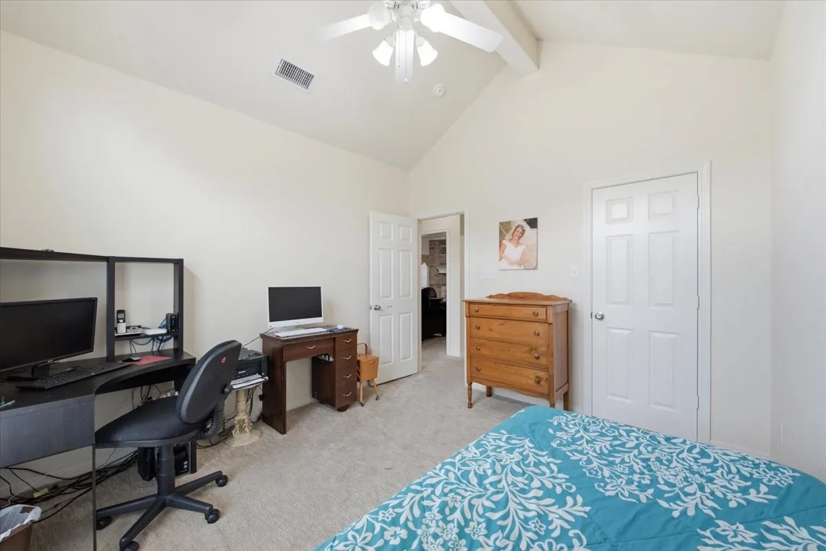 Vaulted ceiling with a ceiling fan, light neutral wall paint, light-colored carpet flooring, and a paneled white door