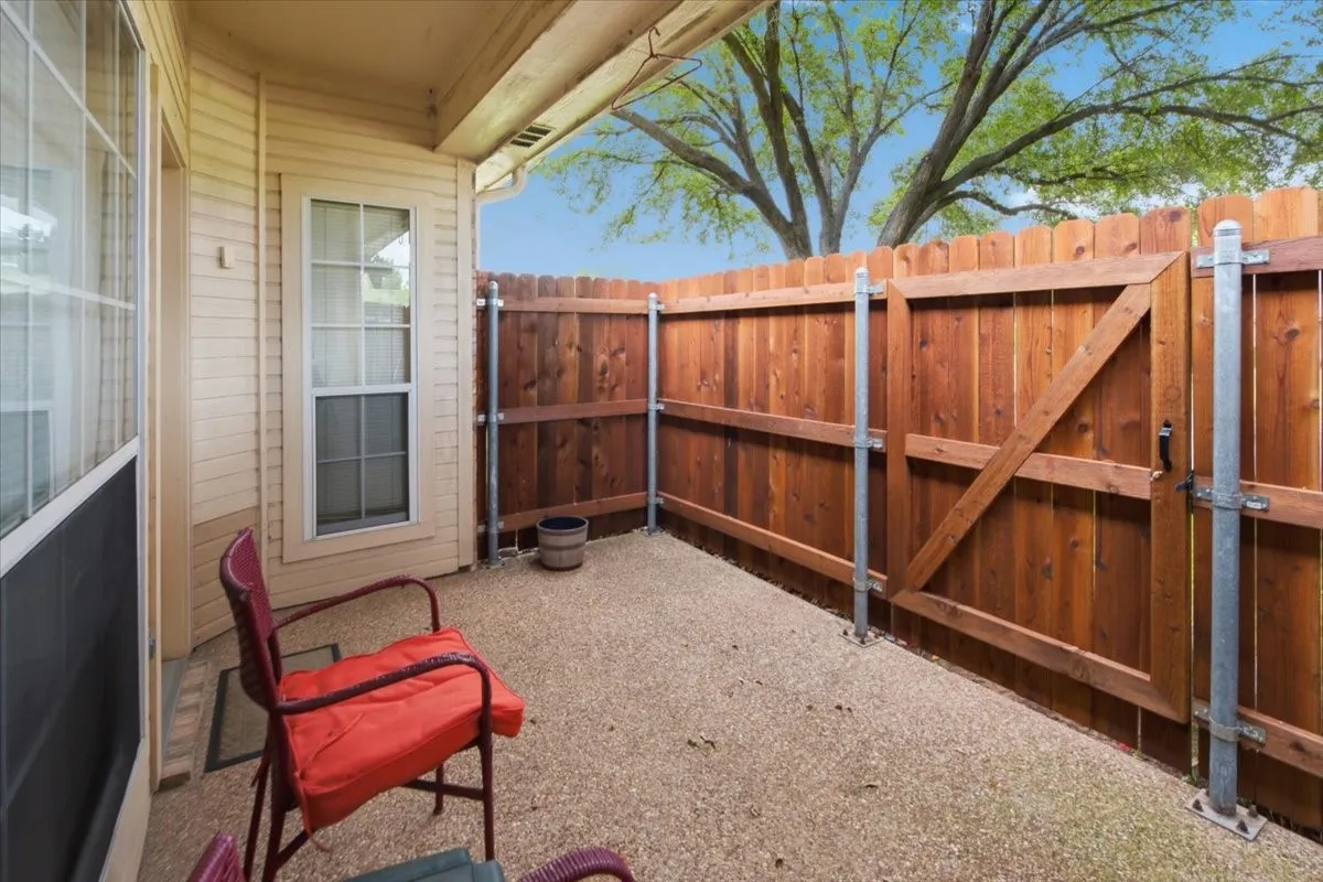 Private outdoor patio featuring a gravel surface, a stained wood privacy fence, and a gate with galvanized metal posts
