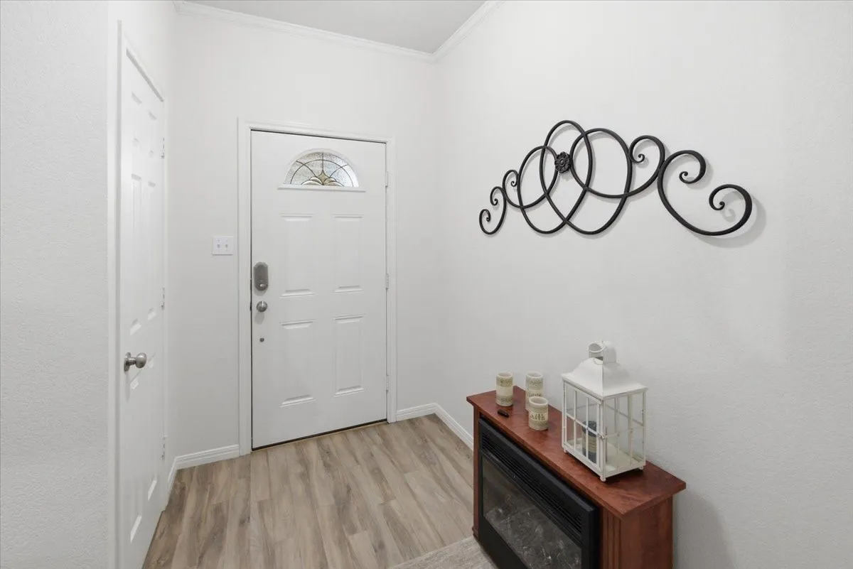 Entryway featuring a white paneled door with decorative glass, wood-finish flooring