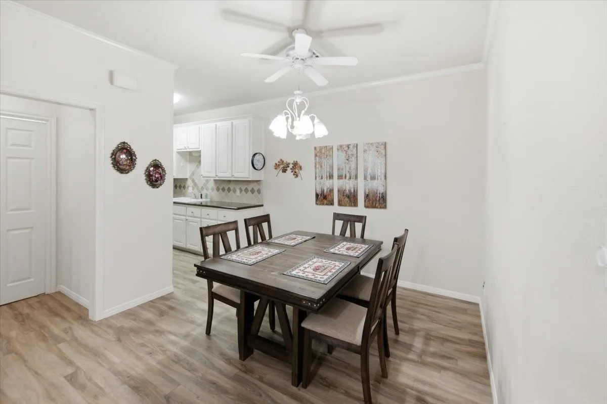 Dining area with wood-finish flooring, crown molding, and a ceiling fan