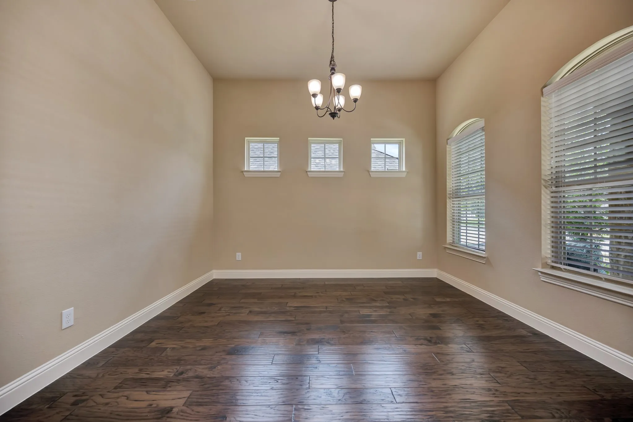 Spacious dining room featuring wood-finish flooring, neutral-toned walls, and white baseboards