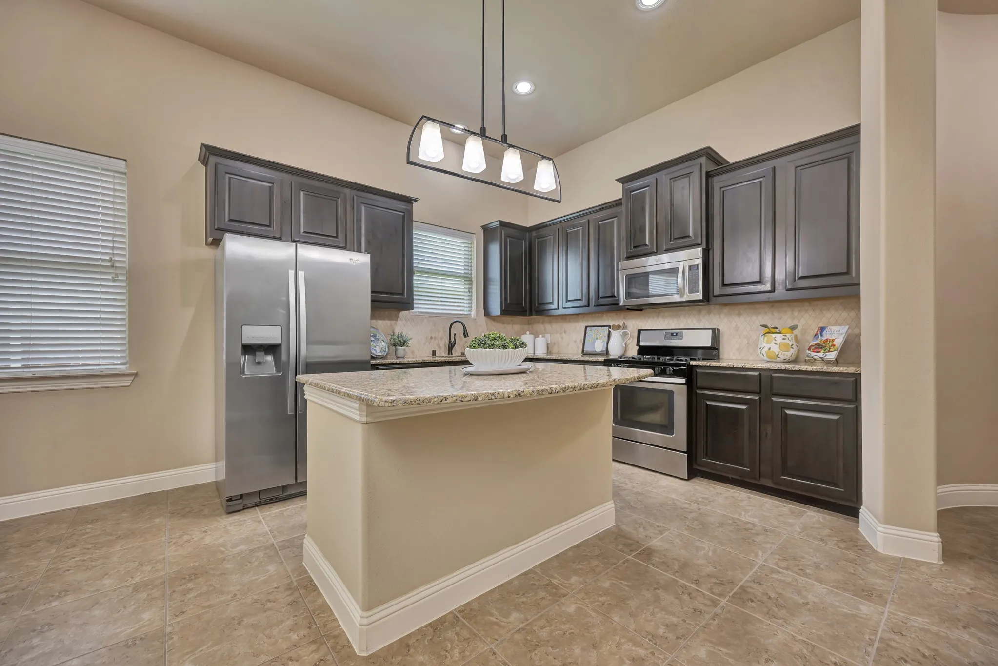 Kitchen featuring a center island with granite countertop, dark wood cabinetry, stainless steel appliances, and tile flooring
