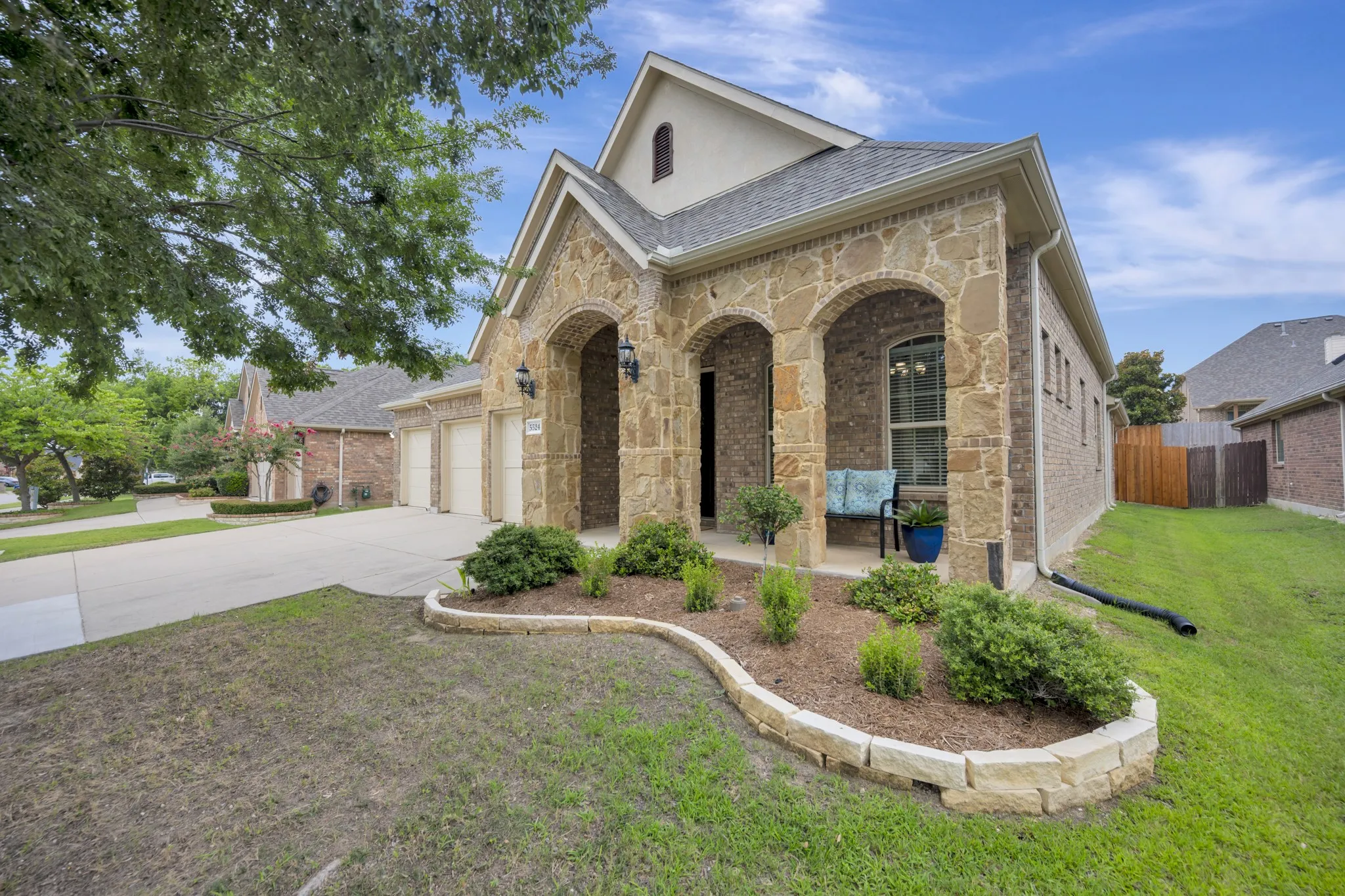 Stone and brick facade featuring an arched covered entry and decorative outdoor coach lights