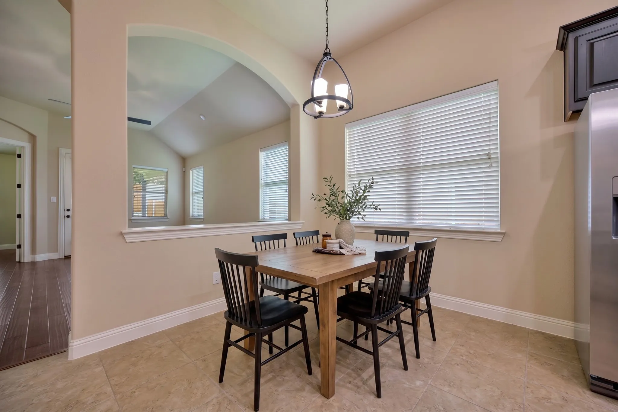 Dining area featuring a central window, decorative pendant lighting, arched architectural opening Virtual staging