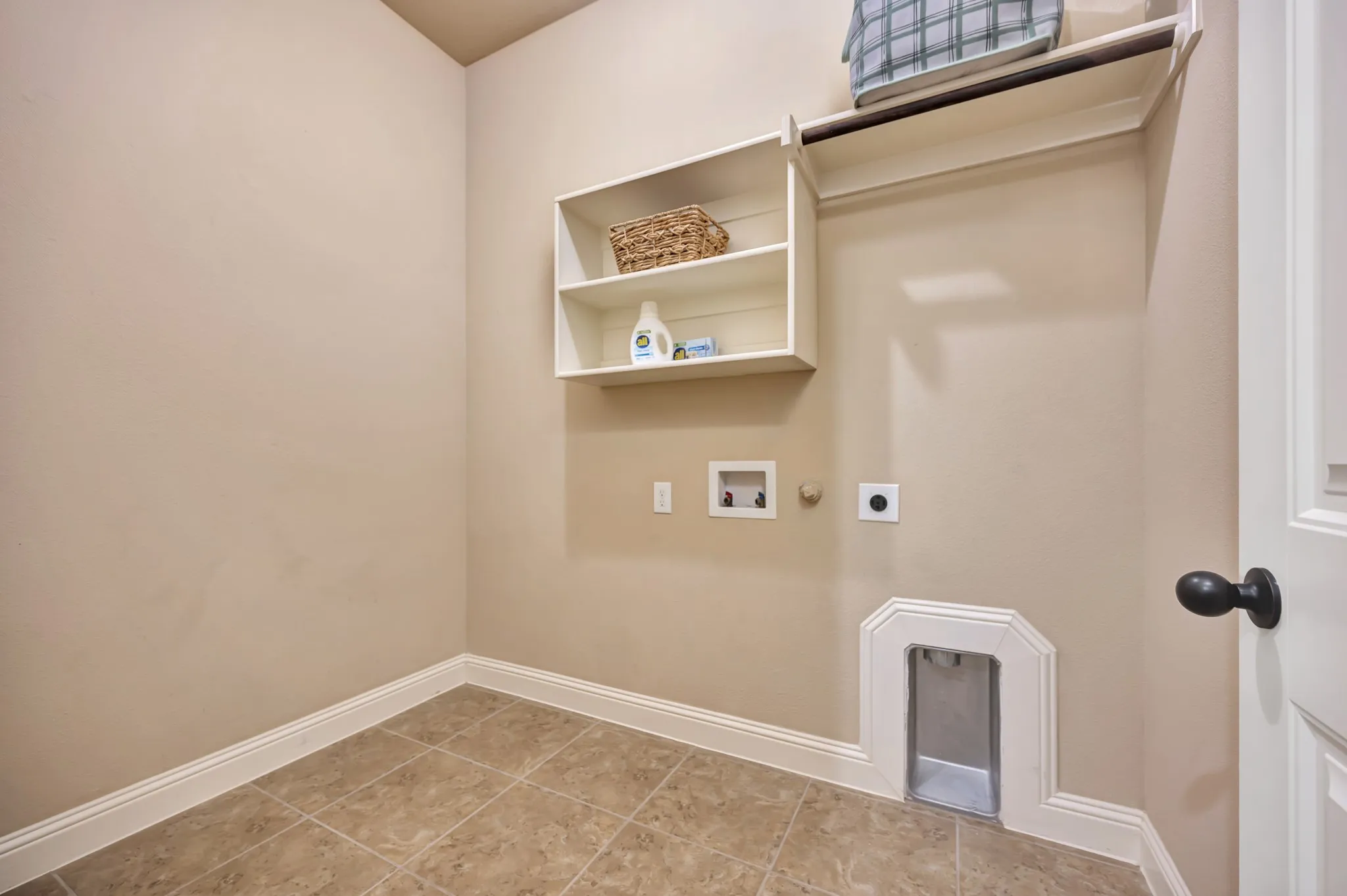 Laundry area featuring neutral wall paint, tile flooring, built-in shelving, and a garment rod