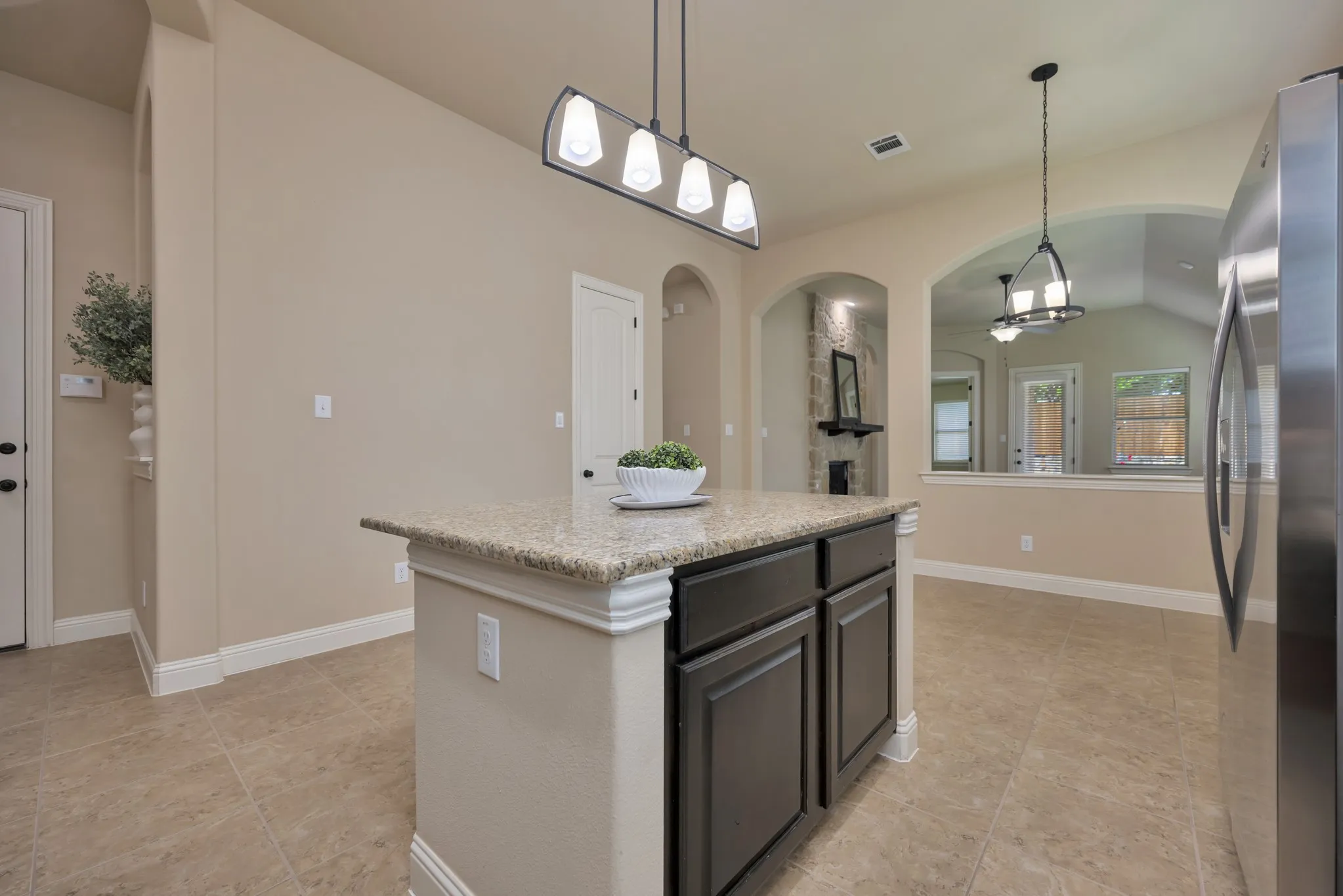 Kitchen island featuring granite countertop, dark wood-finish cabinetry, and a contemporary linear pendant light