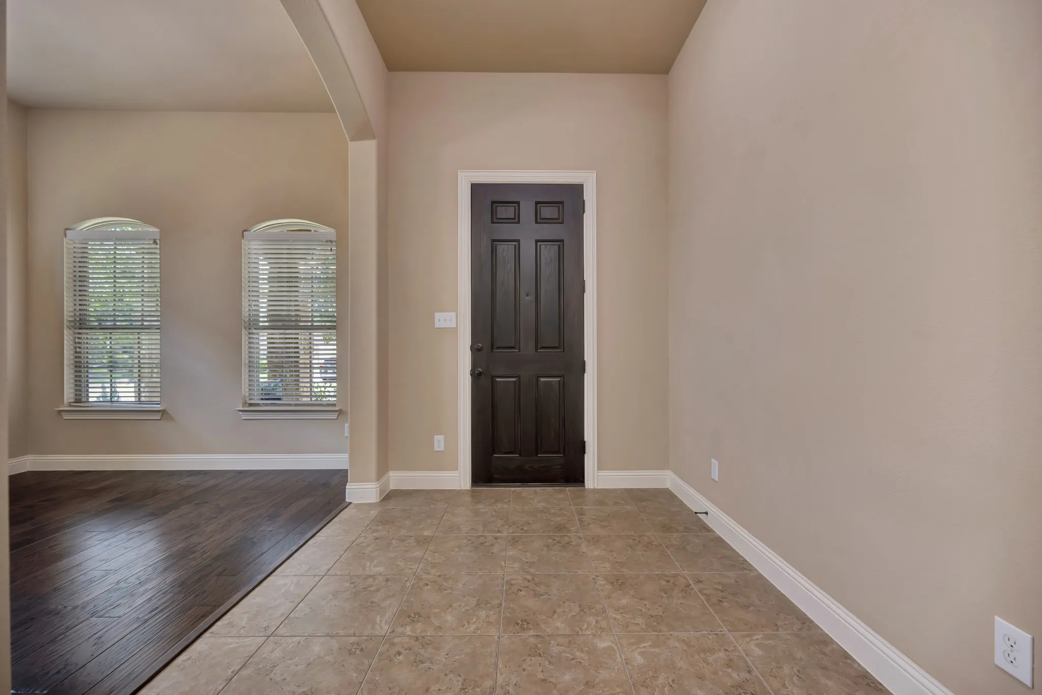 Entryway featuring a dark wood-finish door, light-toned tile flooring, and neutral wall paint