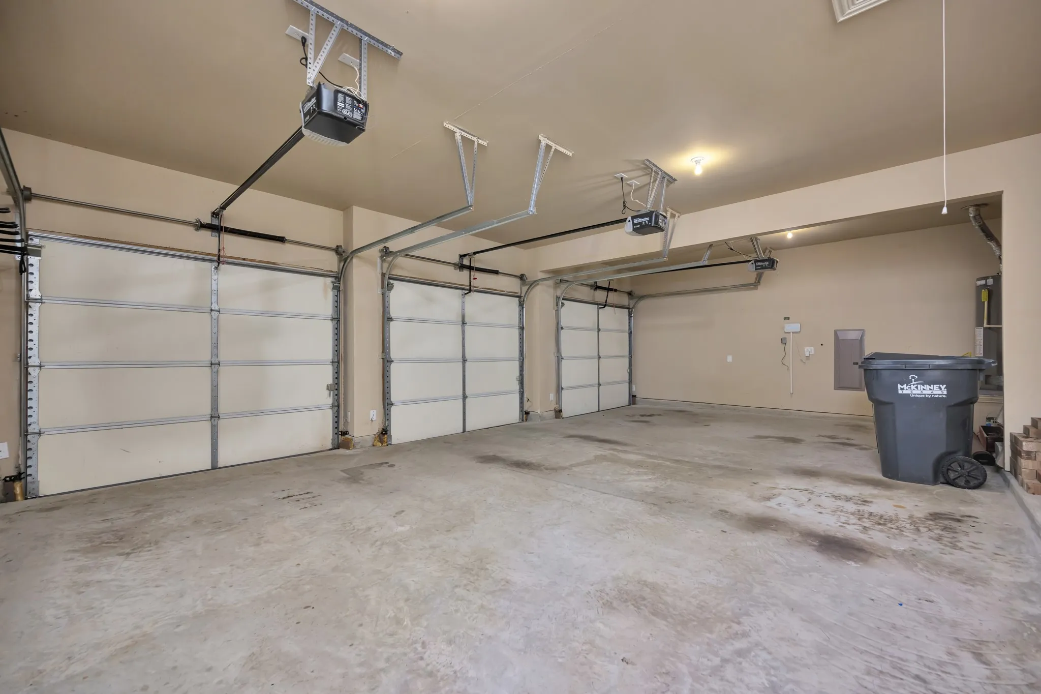 Three-car garage with concrete flooring, automatic garage door openers, and painted walls
