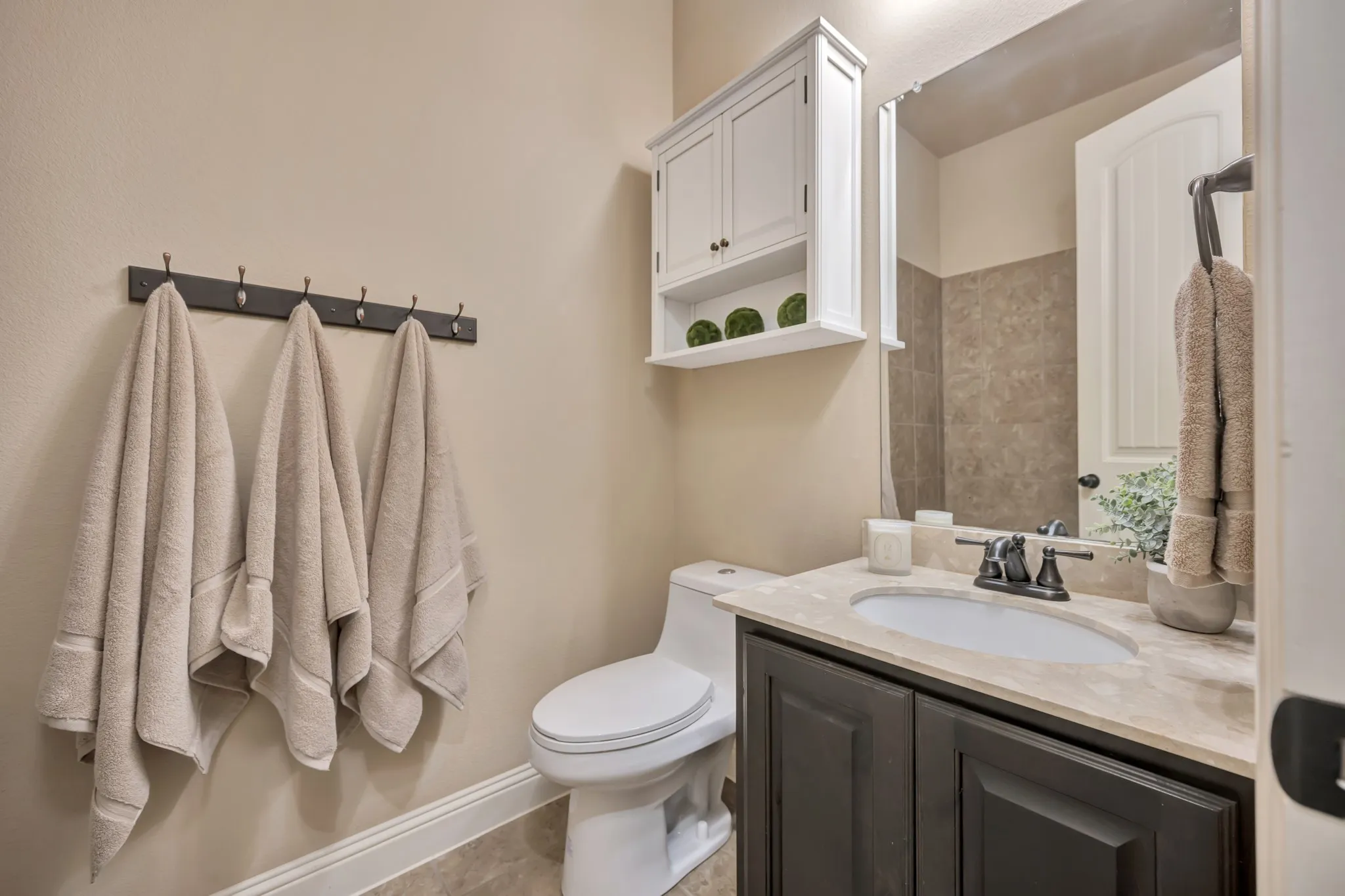 Bathroom featuring a dark wood-finish vanity with an undermount sink, light-toned countertop, and a dark bronze faucet