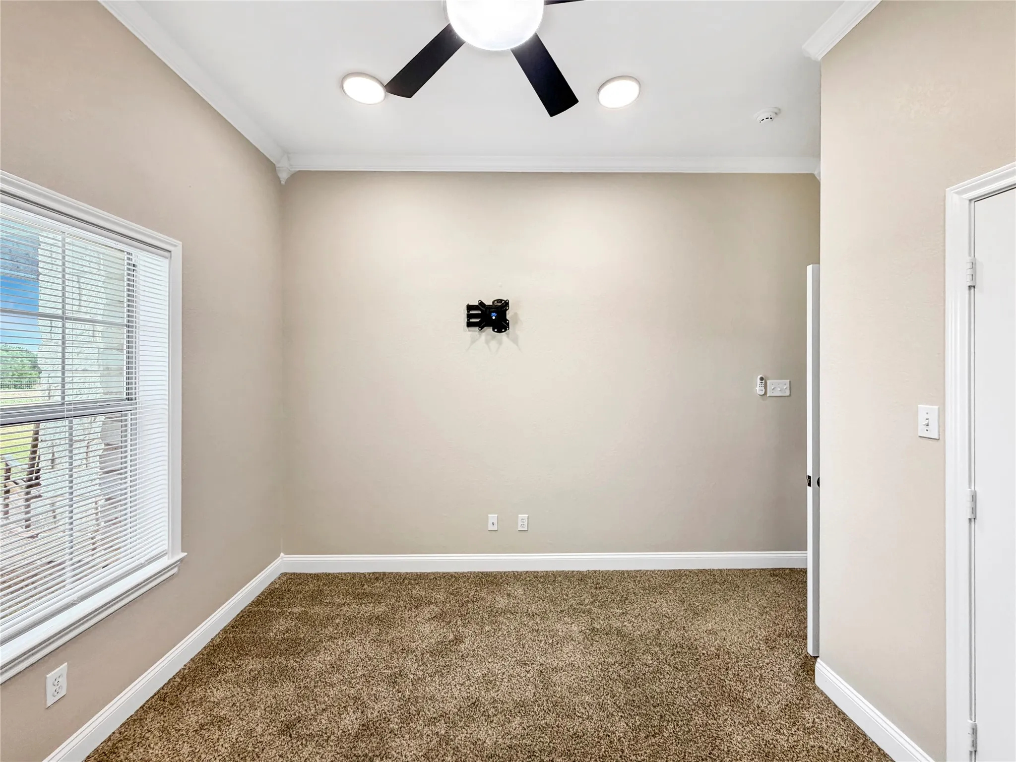 Carpeted room featuring a ceiling fan with integrated lighting, recessed ceiling lights, crown molding, and a window with blinds