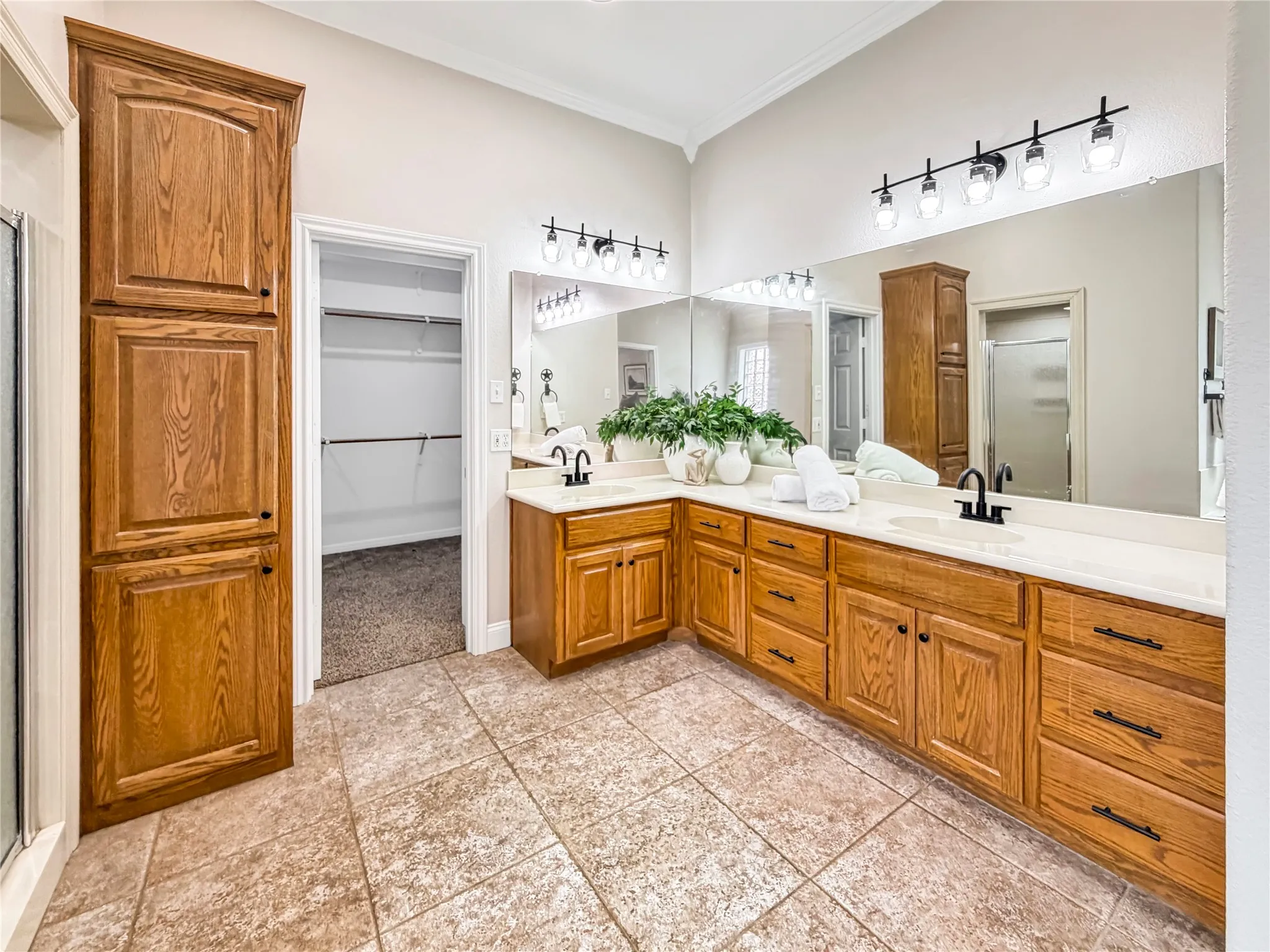 Dual vanity with white countertops, wood cabinetry, and matte black fixtures