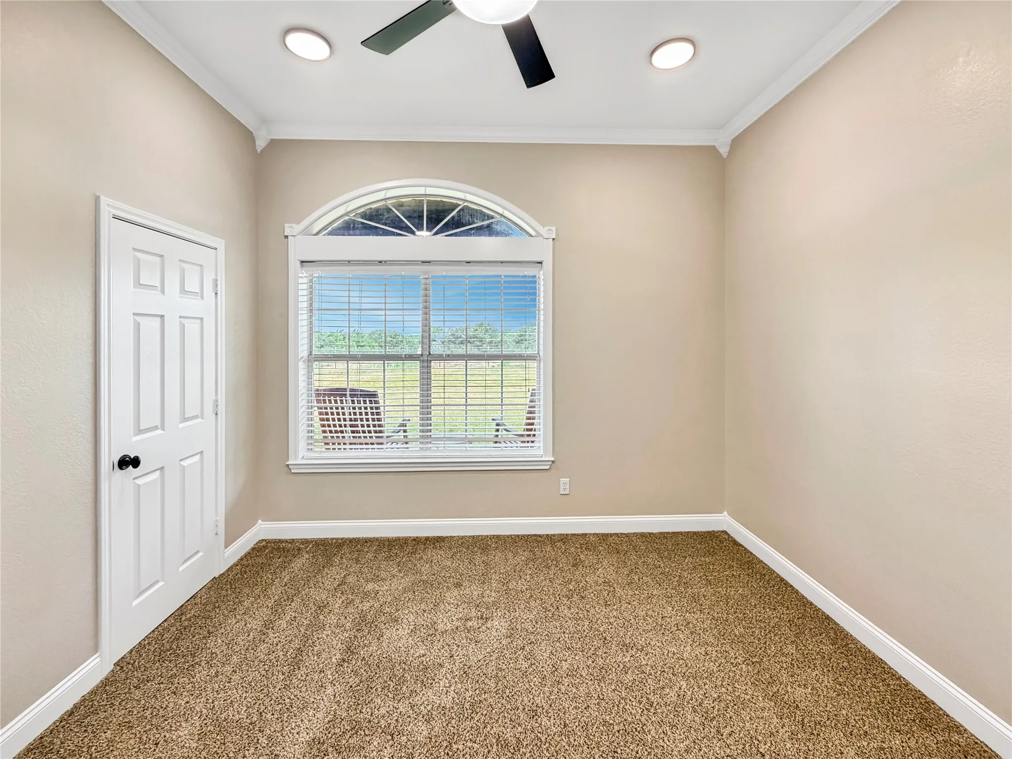Room featuring a large arched window, broad window trim, and horizontal blinds