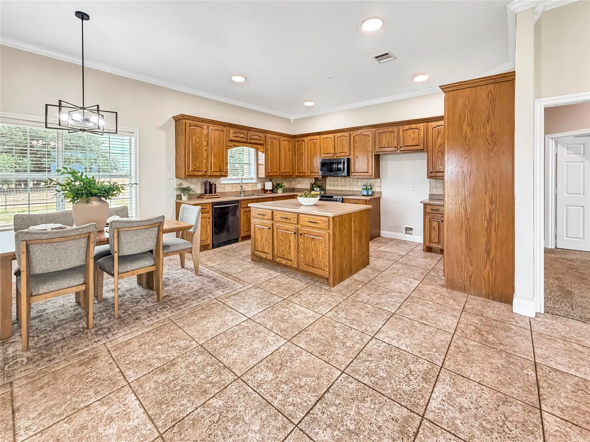 Open-concept kitchen and dining area featuring wood cabinetry, a central island, and black appliances