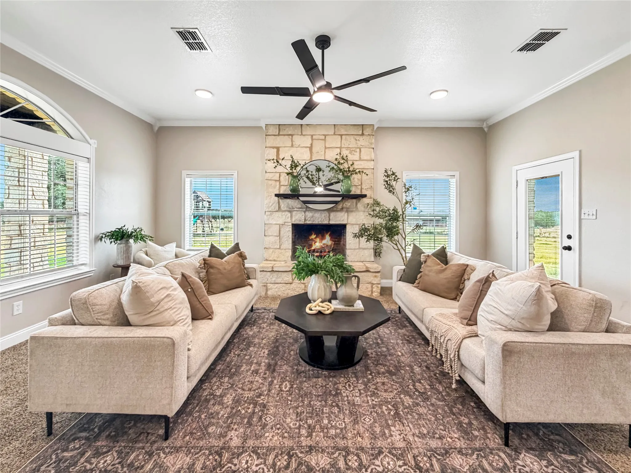 Living room with a stone-clad fireplace and mantel, crown molding, and recessed lighting