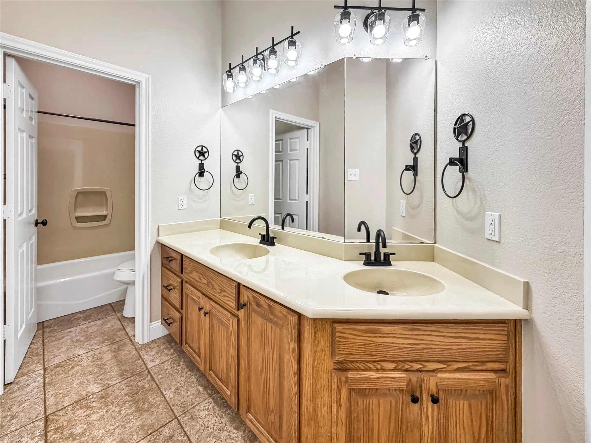 Double vanity featuring light wood-finish cabinetry and a light-toned countertop with integrated sinks