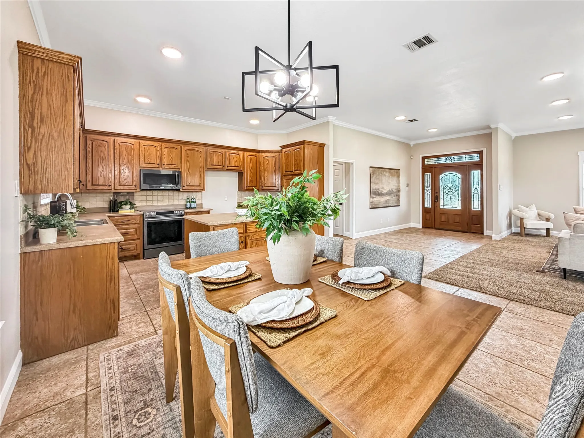 Dining area with a modern linear chandelier, wood-finish table, and tile flooring