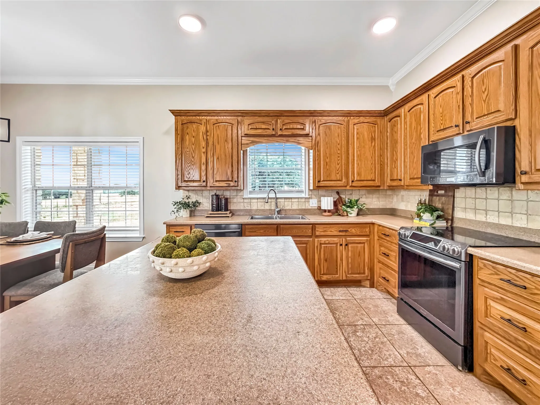 Kitchen featuring an island with ample countertop space, wood cabinetry, built-in microwave, stainless steel range, and tile flooring
