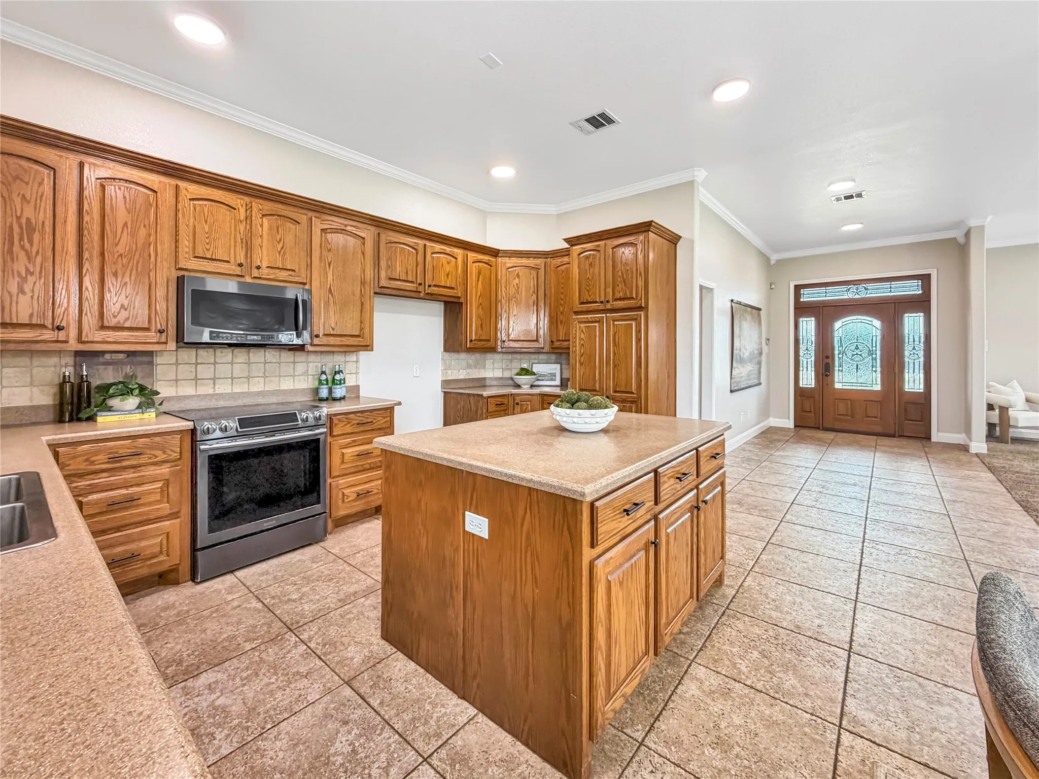Gourmet kitchen featuring wood cabinetry, stone-finish countertops, stainless steel appliances, and a central island