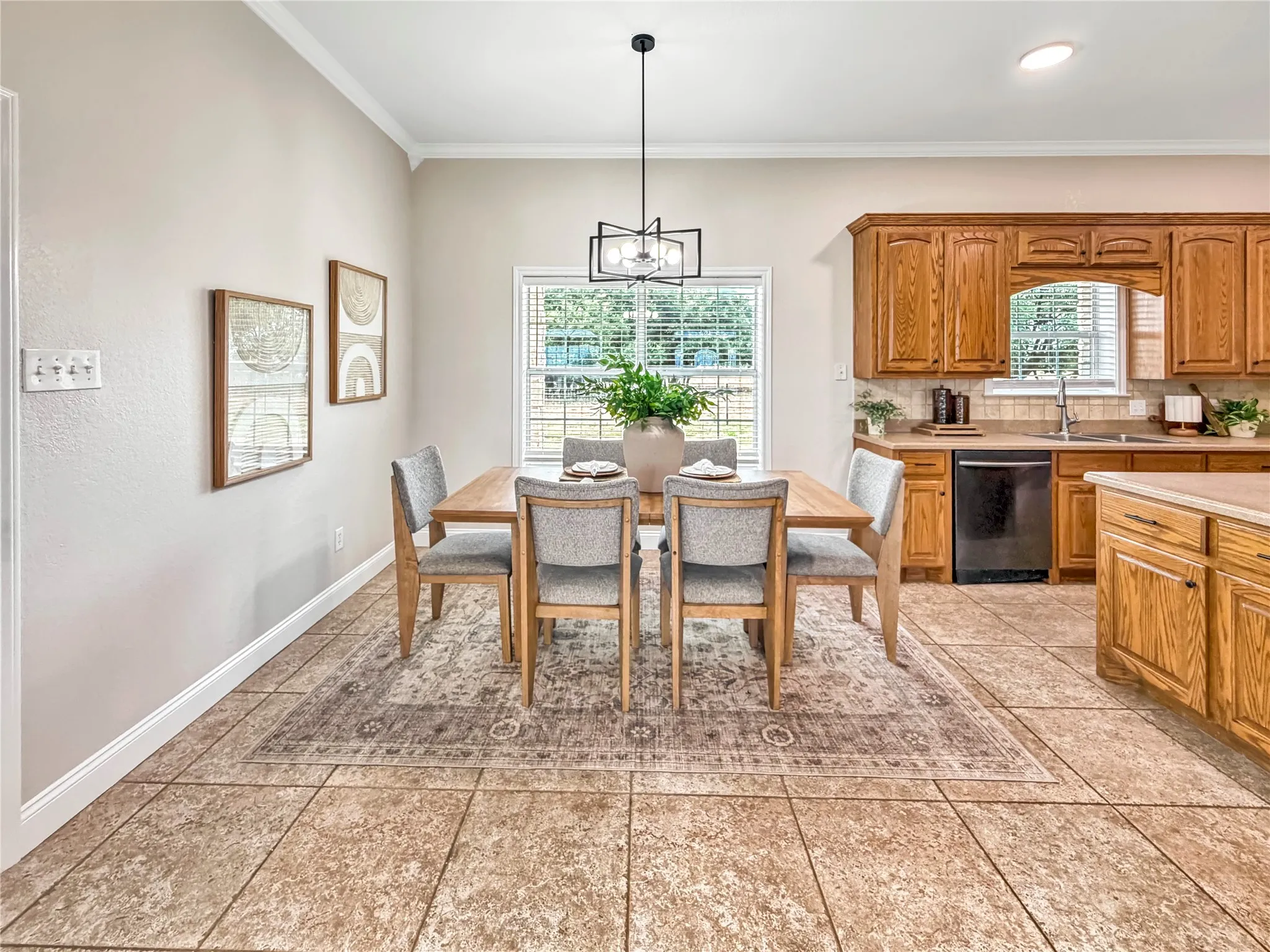 Spacious kitchen and dining area featuring ceramic tile flooring, oak cabinetry, a built-in dishwasher, and a double basin sink