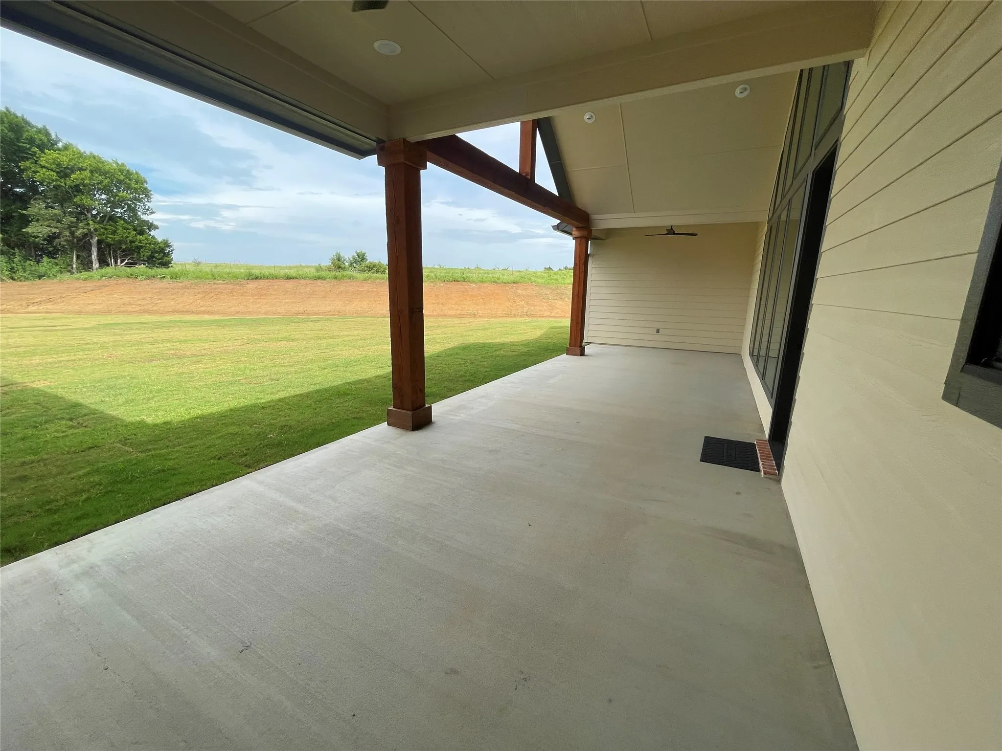 Expansive covered patio featuring a concrete surface, exposed wood structural beams, and recessed lighting