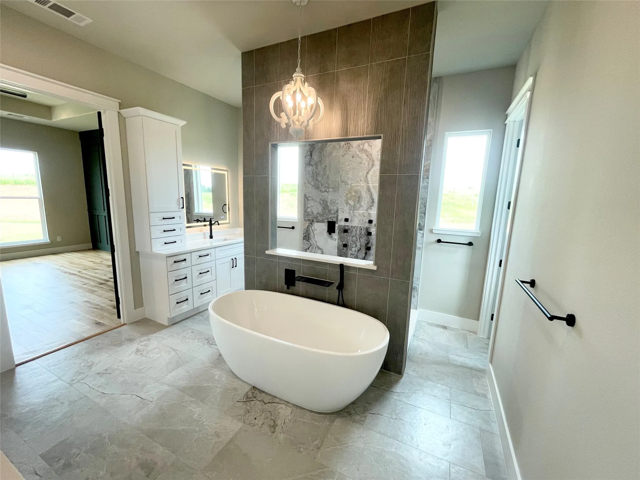 Bathroom featuring a freestanding tub, tile flooring, a dual vanity with white cabinetry, and a walk-in shower with tiled walls and a built-in niche