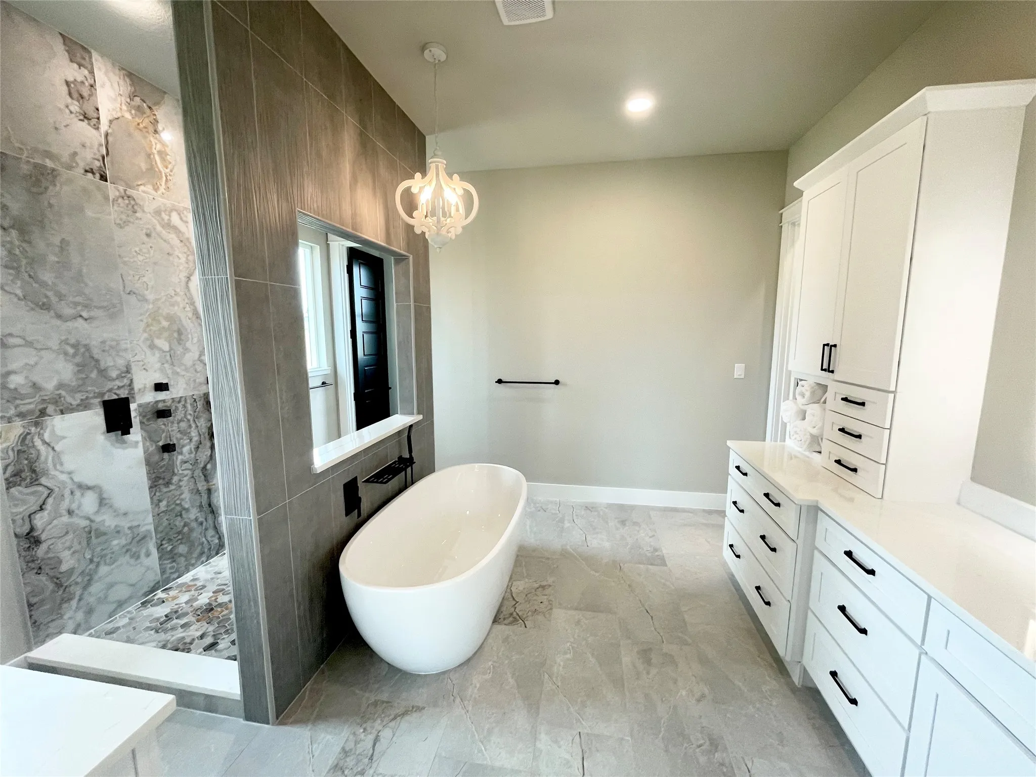 Freestanding soaking tub with an adjacent walk-in shower featuring large format tile