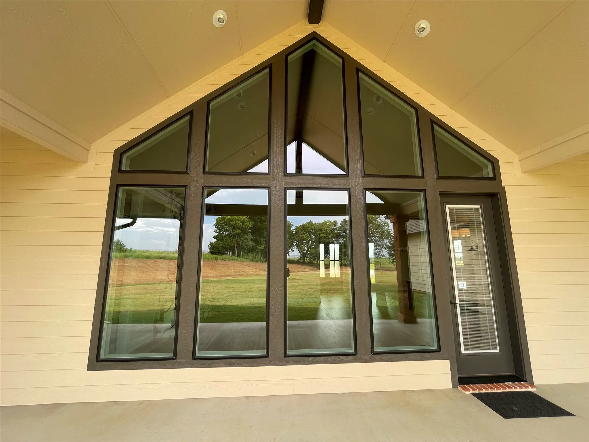 Expansive A-frame window wall with dark frames, a full-light glass entry door, and recessed ceiling lighting