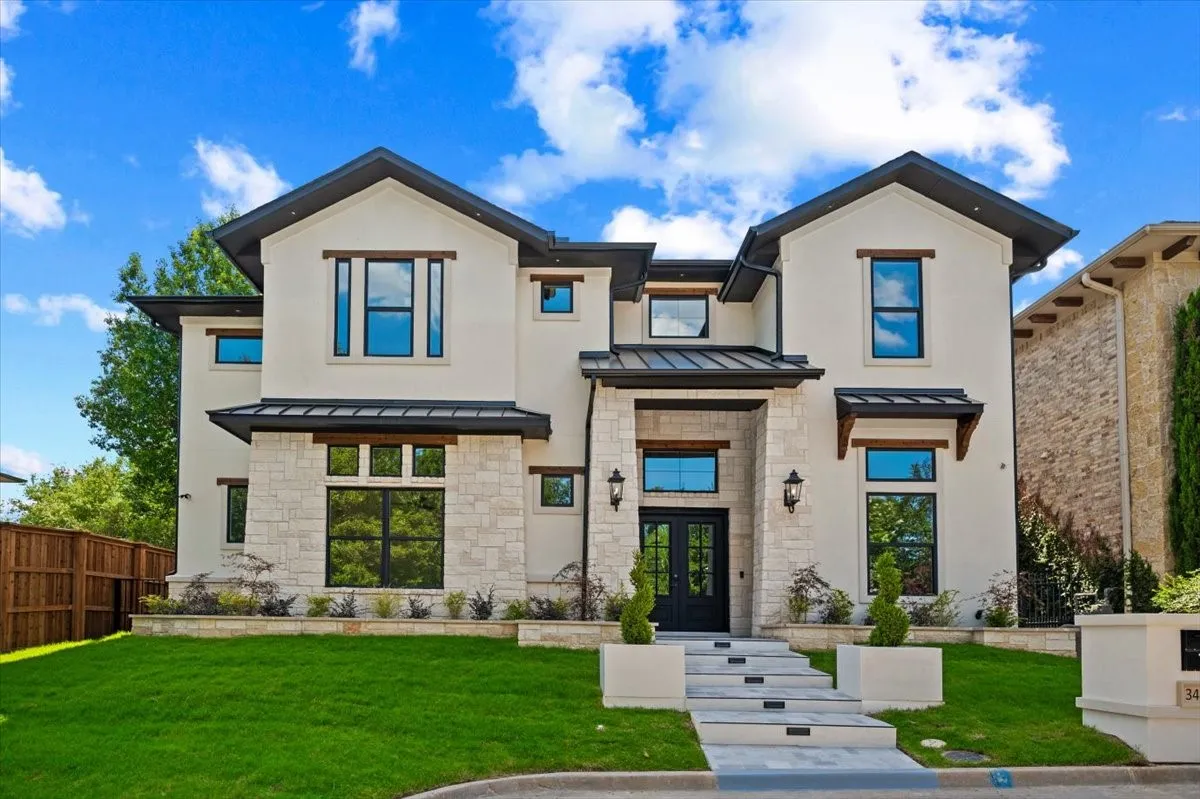 Contemporary stucco and stone-clad exterior with prominent black-framed windows