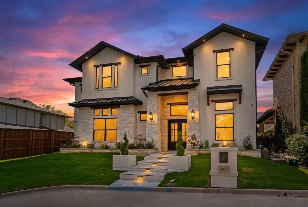 Contemporary two-story residence featuring a stucco and stone facade, dark trim accents, and a prominent double-door entry