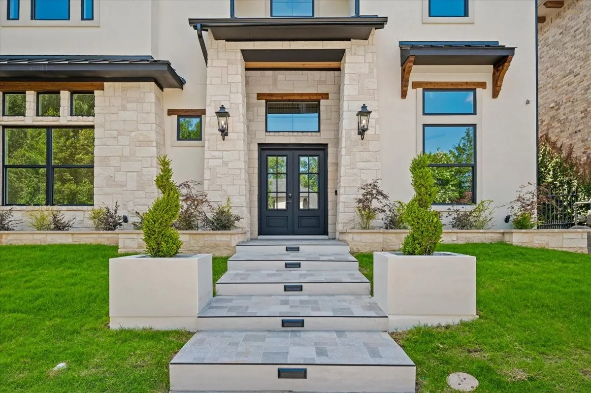 Modern exterior featuring a stone and stucco facade, a double-door entry, and a multi-level stone staircase with integrated lighting