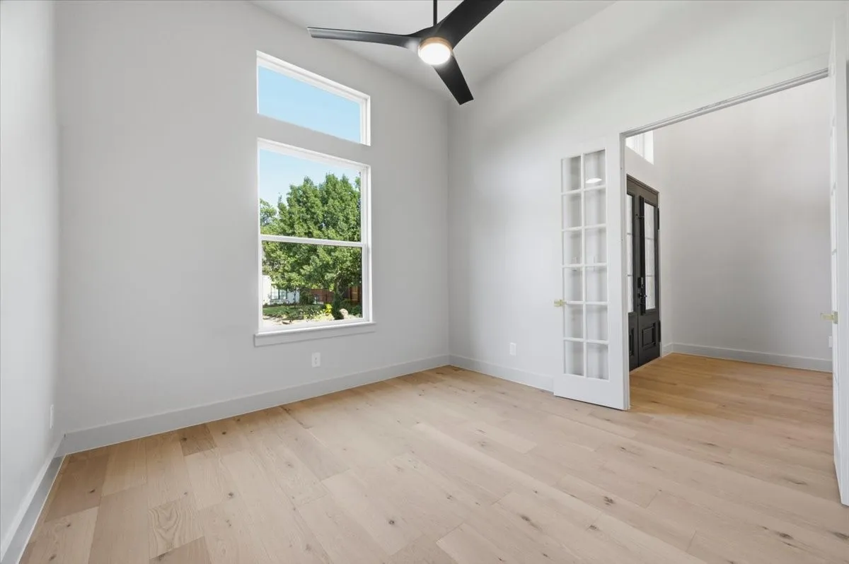 Room featuring wood-finish flooring, vaulted ceiling, and a contemporary ceiling fan