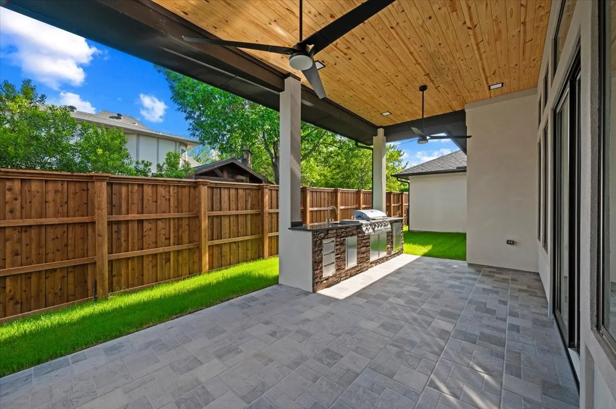 Covered outdoor patio featuring a built-in grill station with stone-finish and stainless steel accents