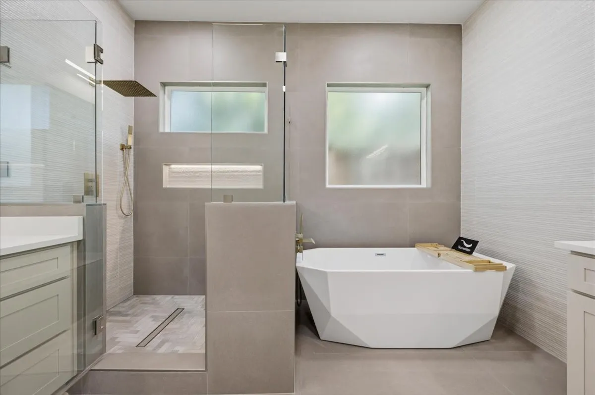 Modern bathroom featuring a freestanding geometric bathtub and a glass-enclosed shower with a linear drain