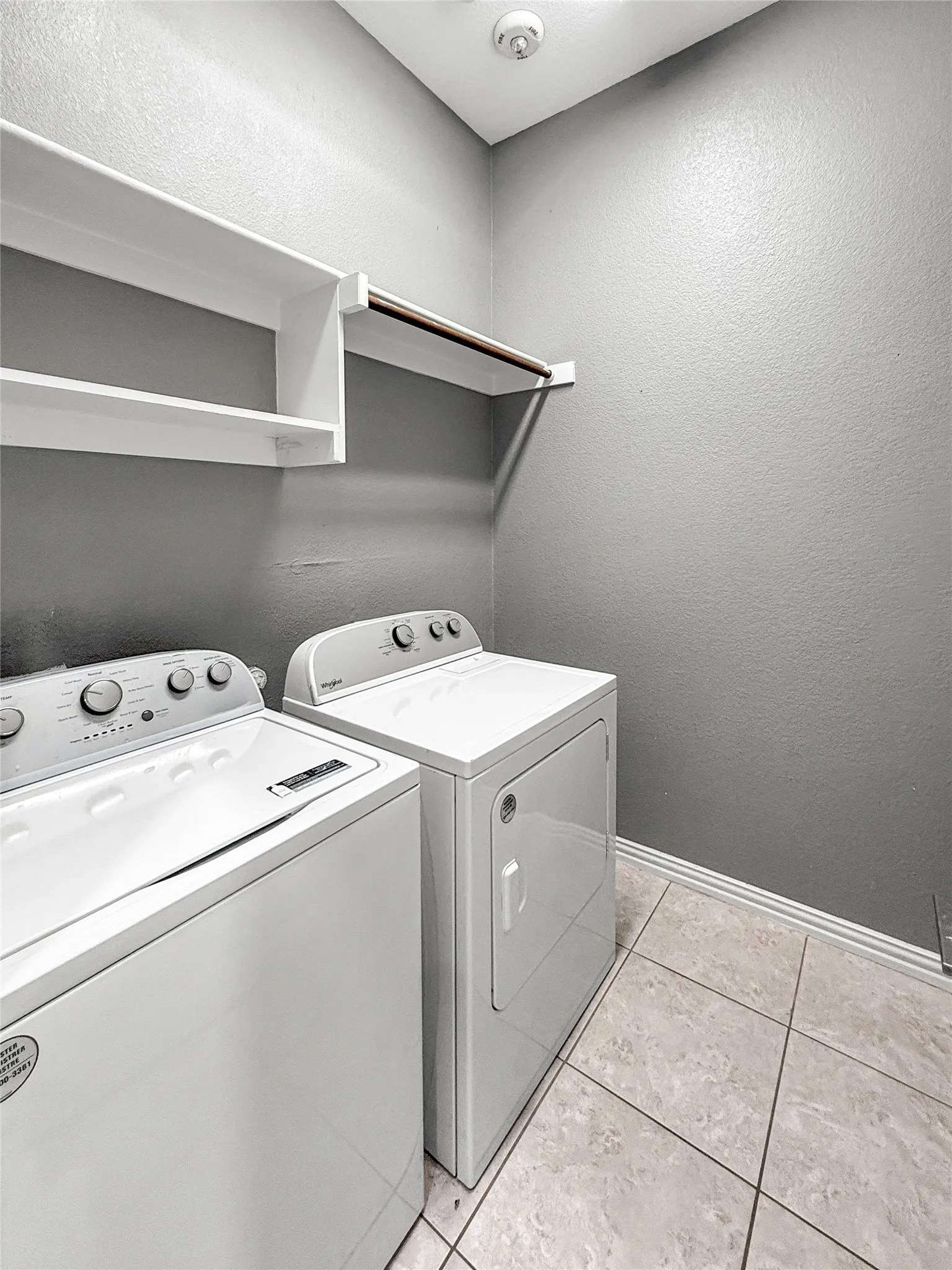 Laundry area with tile flooring, baseboard trim, and a white ceiling