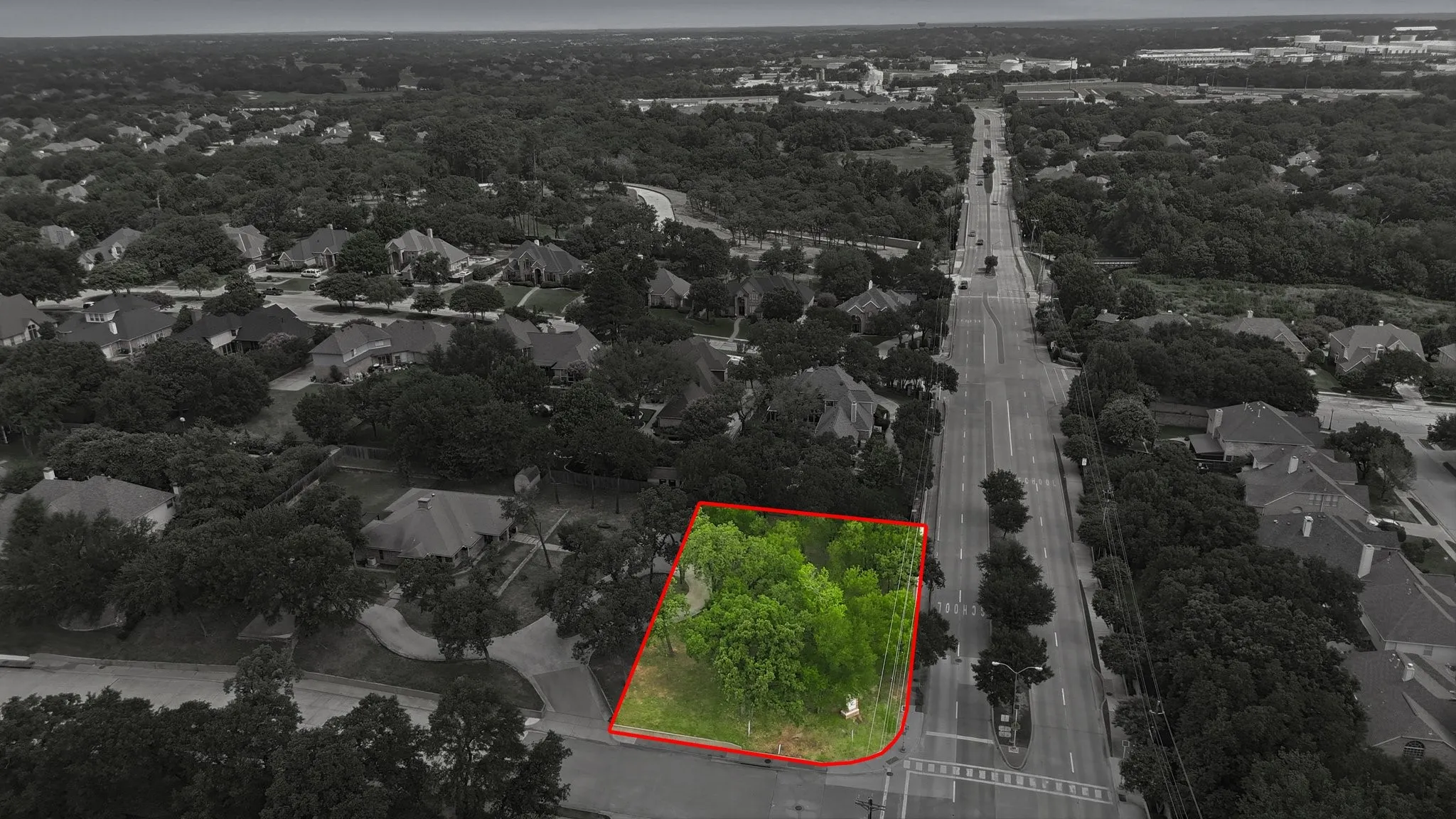 Expansive lot with mature trees, situated at a road intersection, featuring a clear boundary line