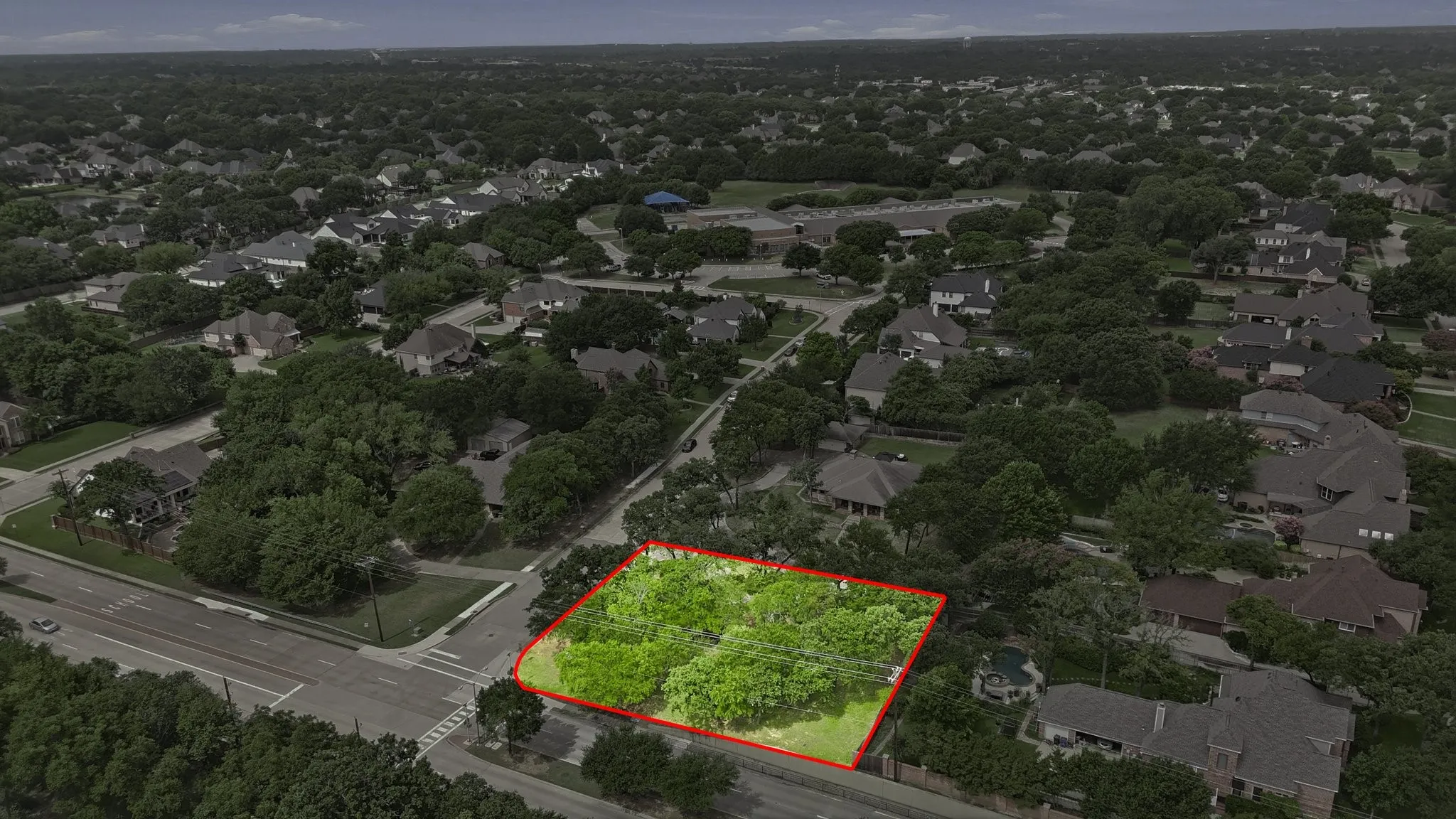 Aerial perspective of a verdant land parcel outlined in red, featuring mature trees and lush greenery